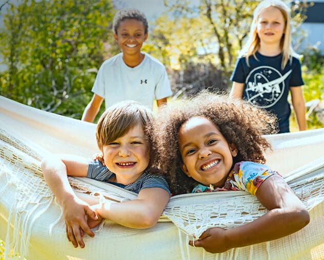 Kinder spielen lachend in einer Hängematte