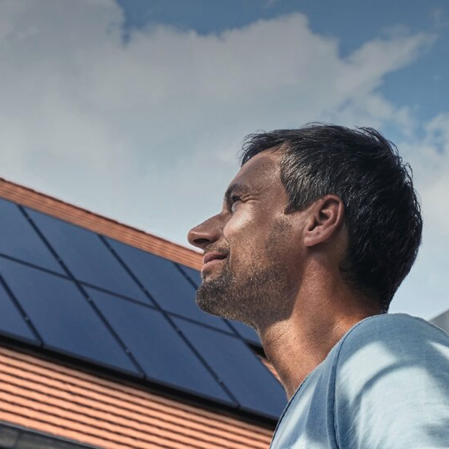 Mann, der auf eine Photovoltaik-Anlage auf ein Dach schaut