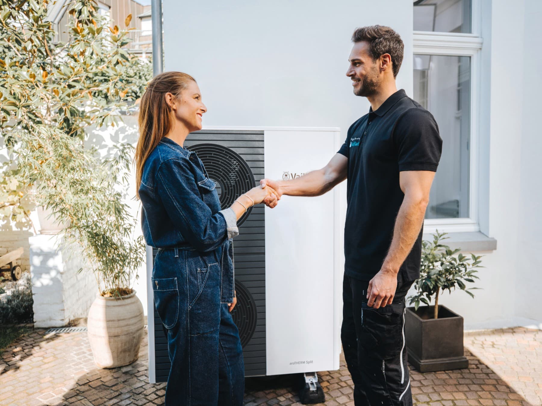 Fachhandwerker mit Kundin vor Wärmepumenausseneinheit