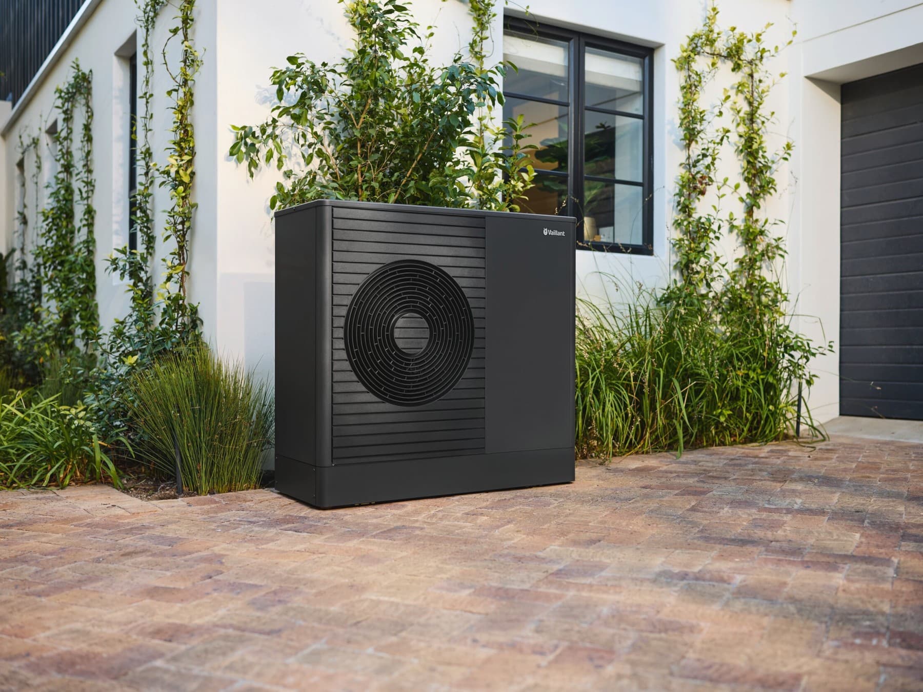 Die neue Vaillant Wärmepumpe aroTHERM plus vor einem Wohnhaus.