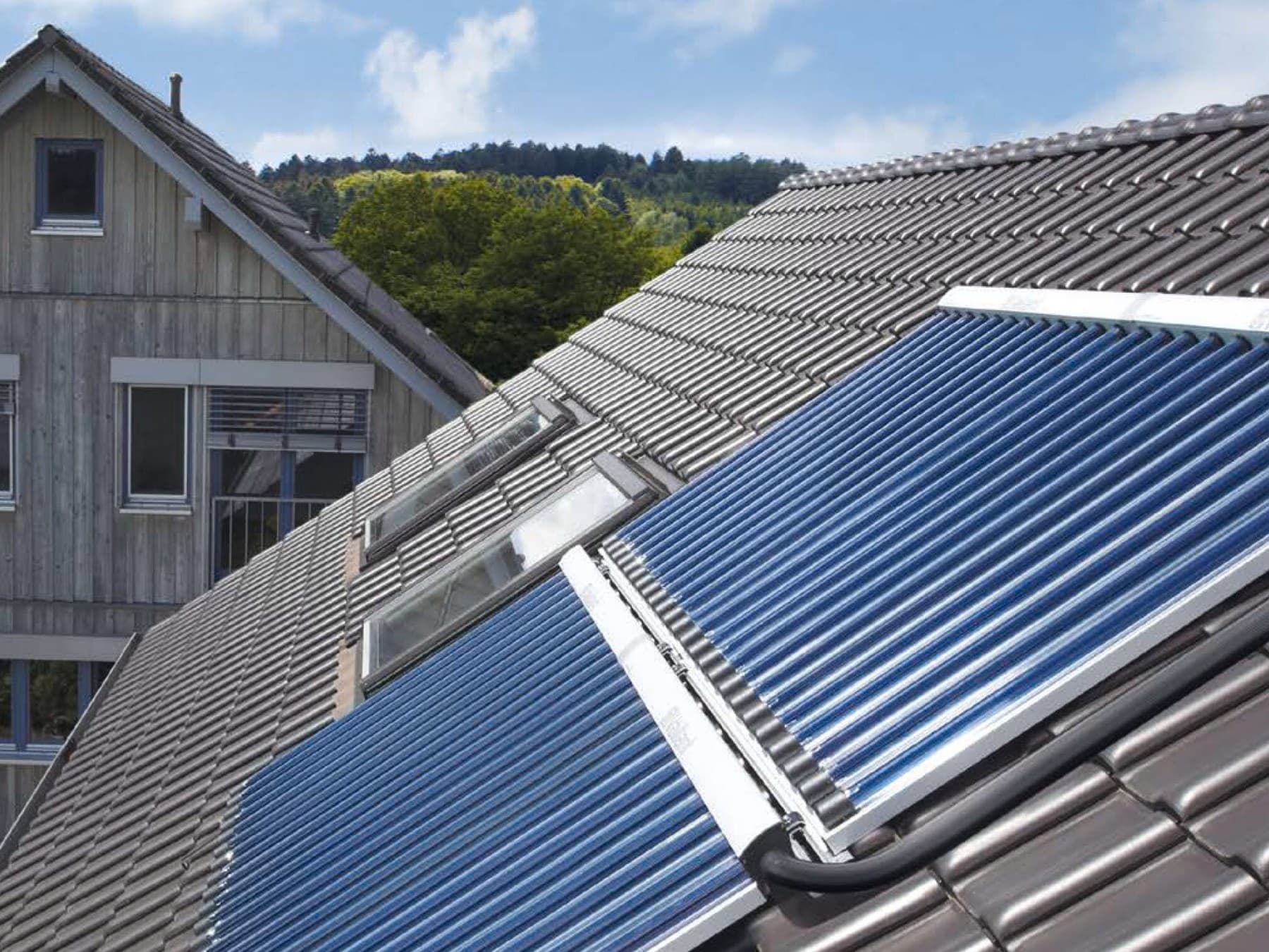 Eine Solaranlage mit Röhrenkollektoren von Vaillant auf einem Hausdach im Sonnenschein.