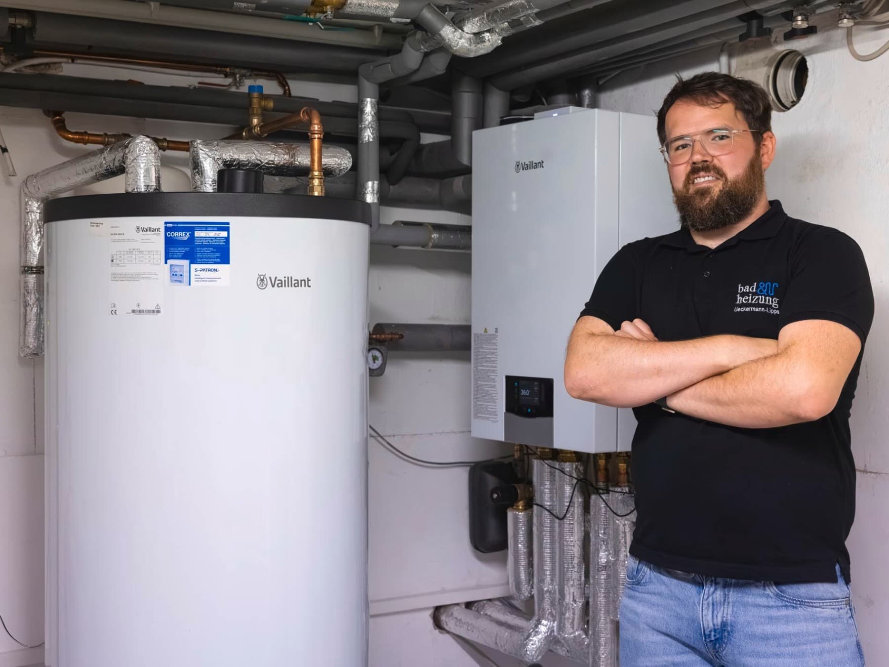 Heizungsfachmann im Heizungskeller neben mehreren Vaillant Geräten