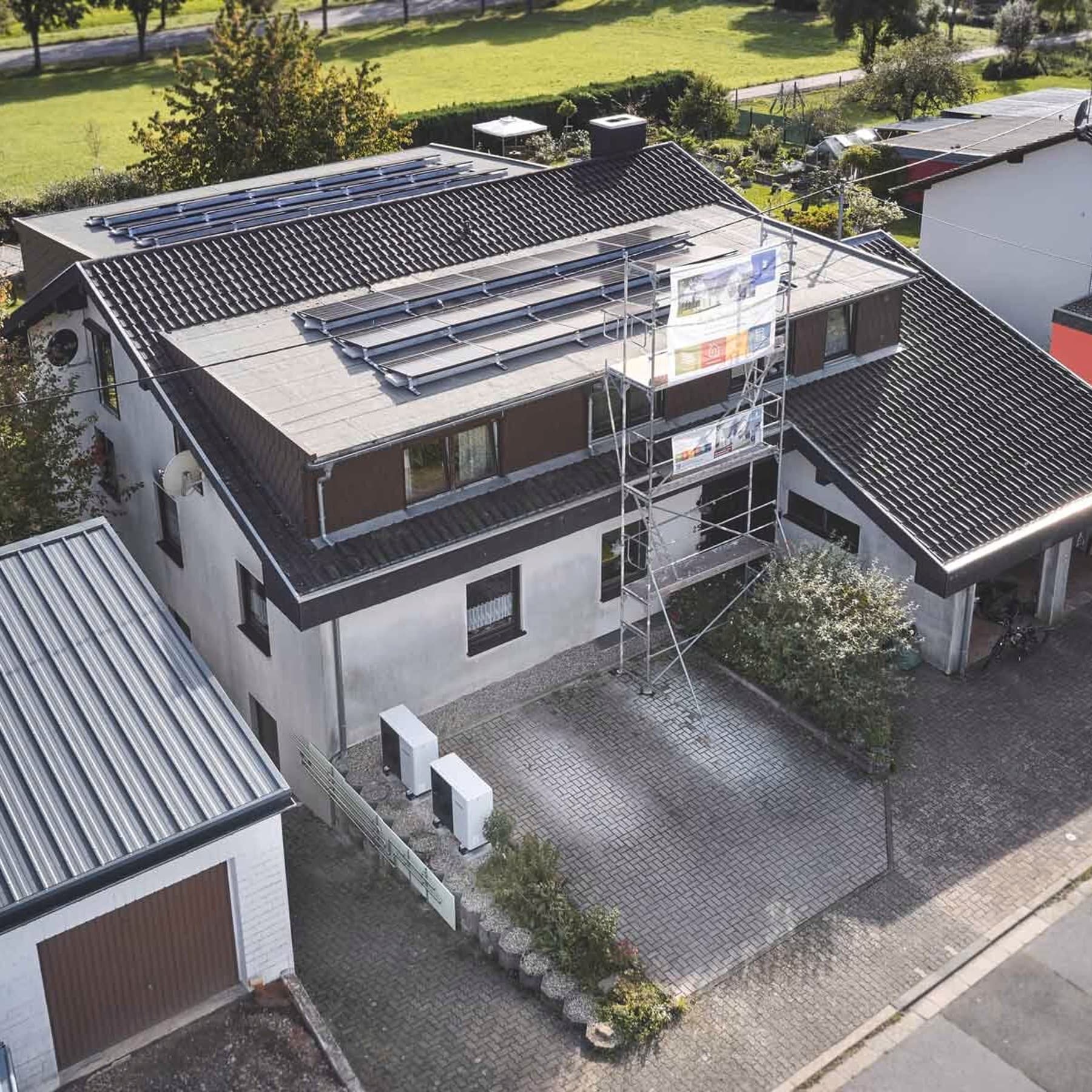Zweifamilienhaus mit Photovoltaik auf dem Dach und Wärmepumpen vor dem Haus, fotografiert aus der Vogelperspektive