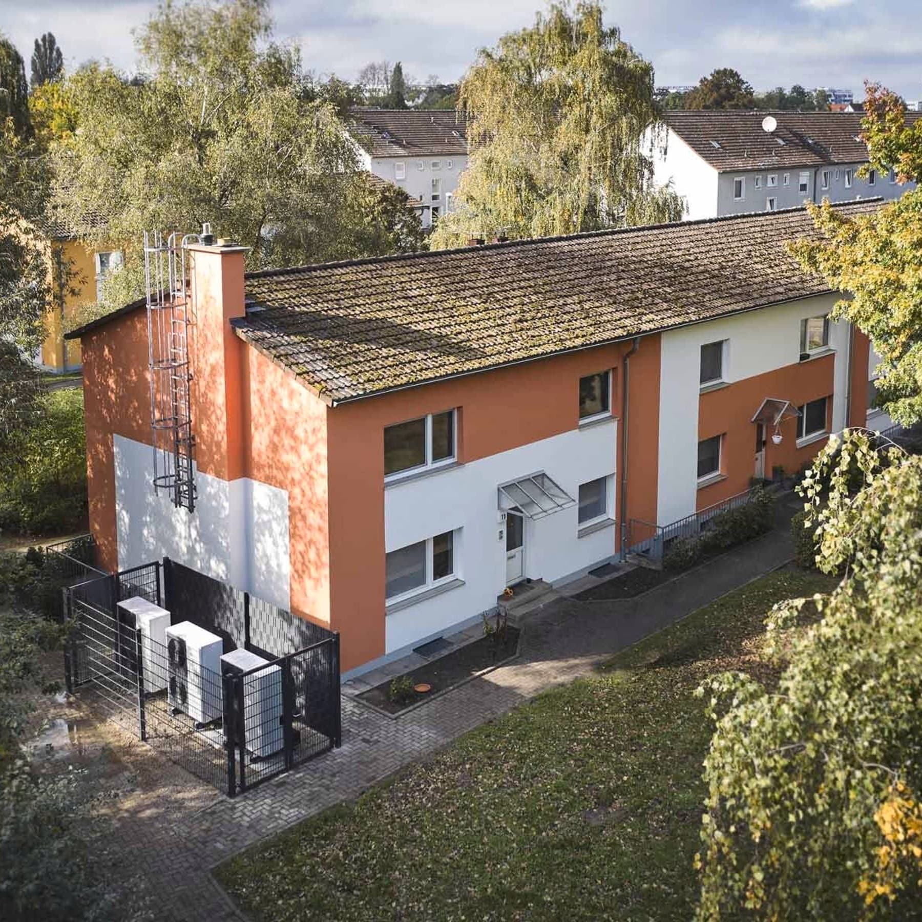 Mehrfamilienhaus mit Wärmepumpen davor