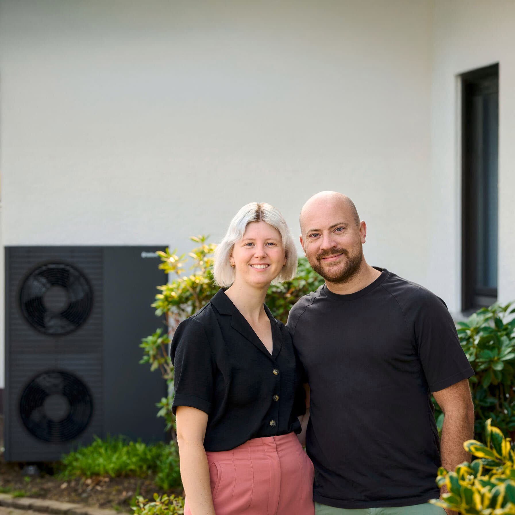 Familie Schiedeck, die lächelnd vor ihrer neuen Vaillant Wärmepumpe steht