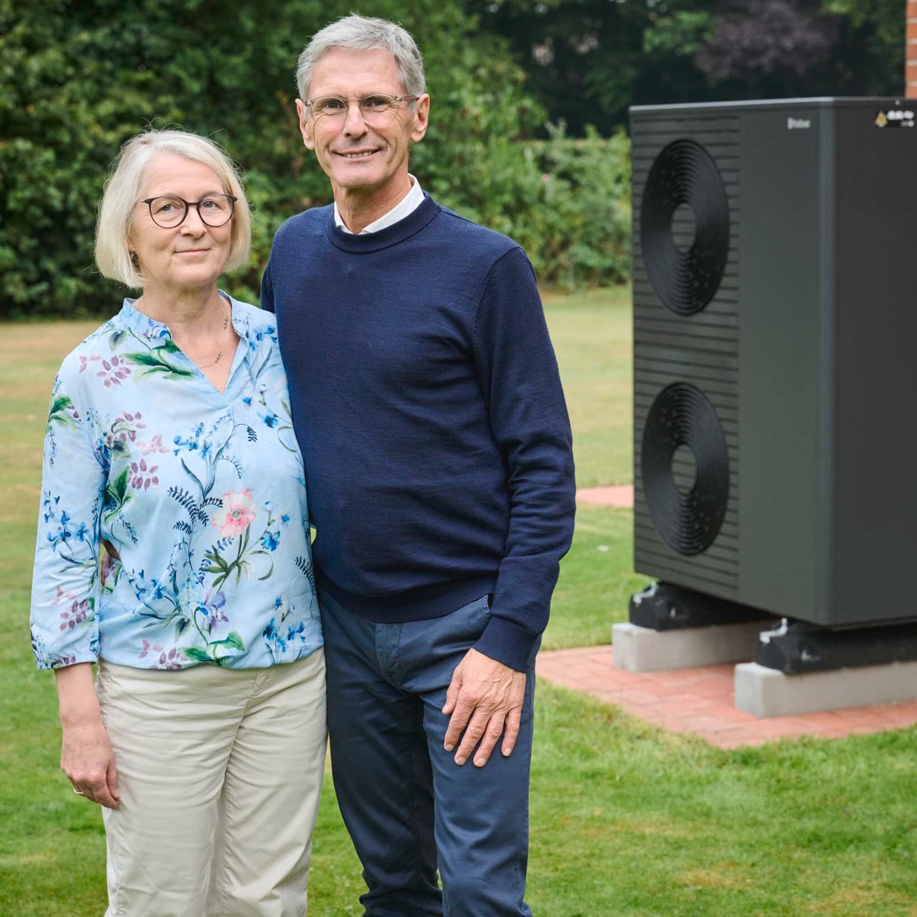 Renate und Wolfgang große Holthaus stehen in Ihrem Garten neben der Wärmepumpe