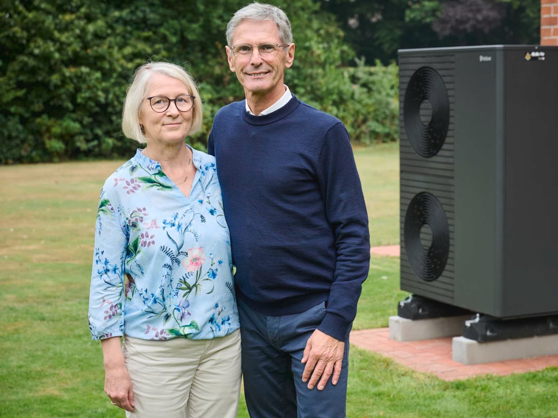 Foto der Hausbesitzer im Garten vor ihrer schwarzgrauen Vaillant Wärmepumpe