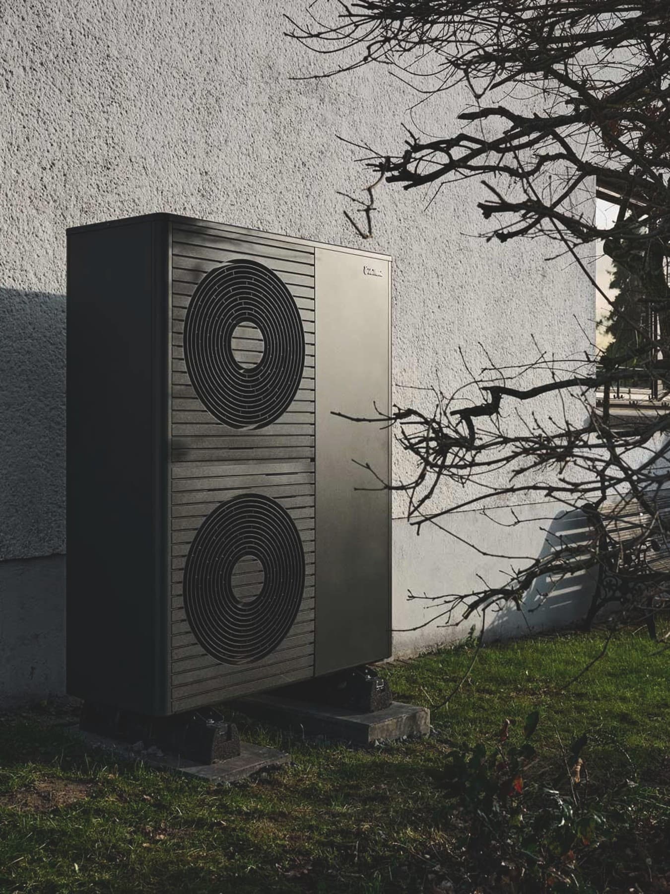 Doppelstöckige Wärmepumpe aroTHERM plus im Vorgarten vor weißer Hauswand