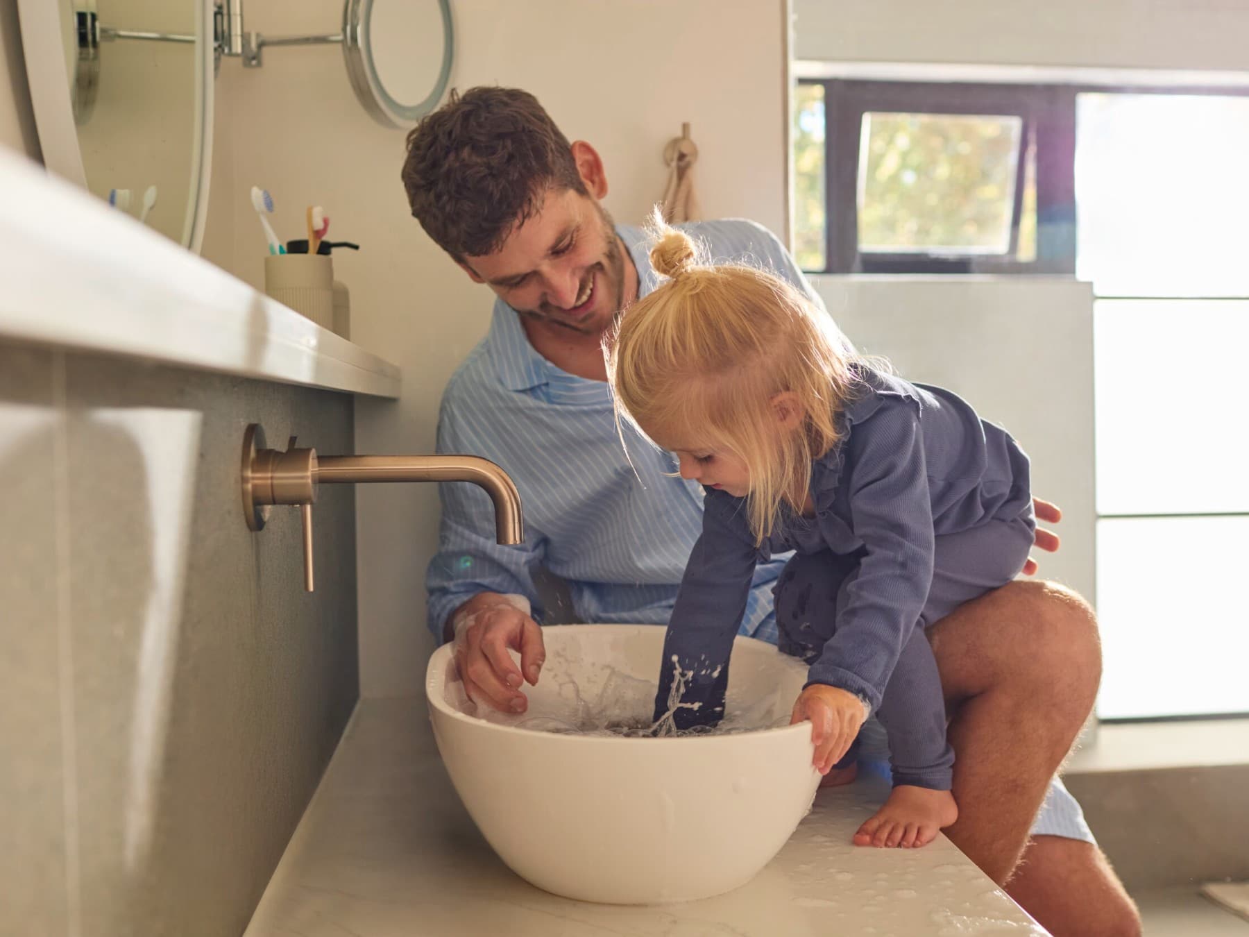 Vater spielt mit kleiner Tochter am Waschbecken