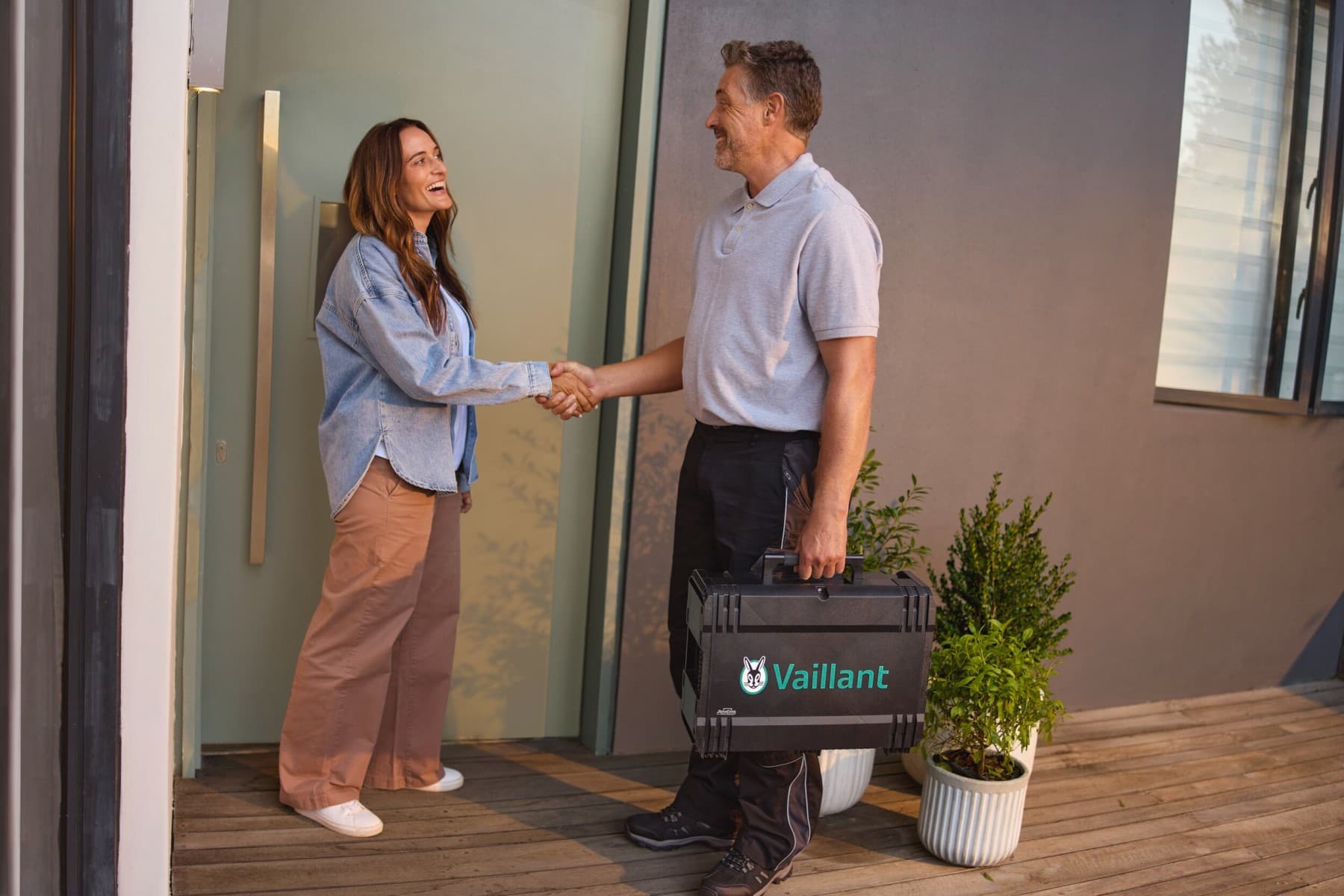 Heizungstechniker und Frau stehen händeschüttelnd vor einer Haustüre