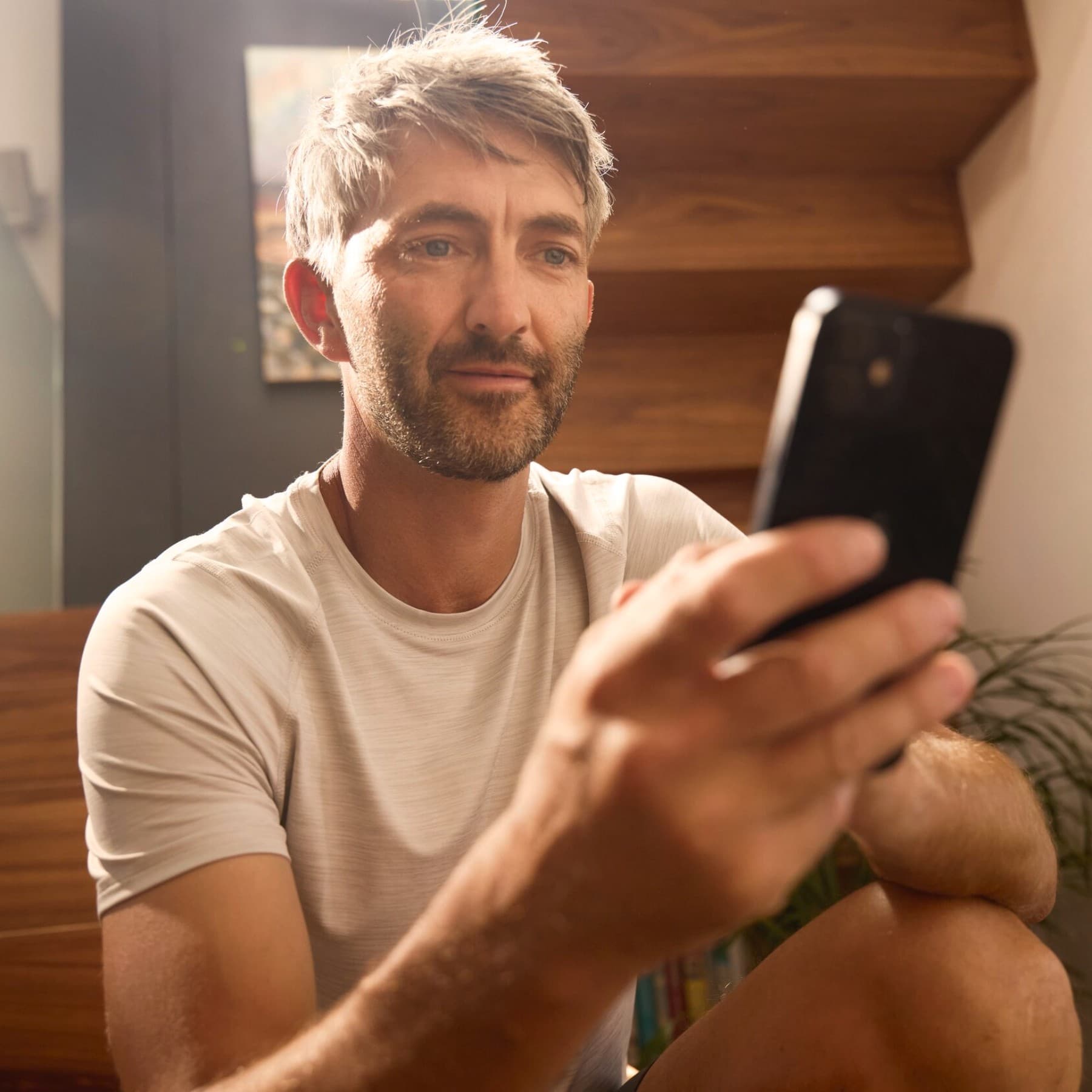 Mann prüft auf seinem Smartphone die aktuellen Förderungen für Wärmepumpen im Hybridsystem