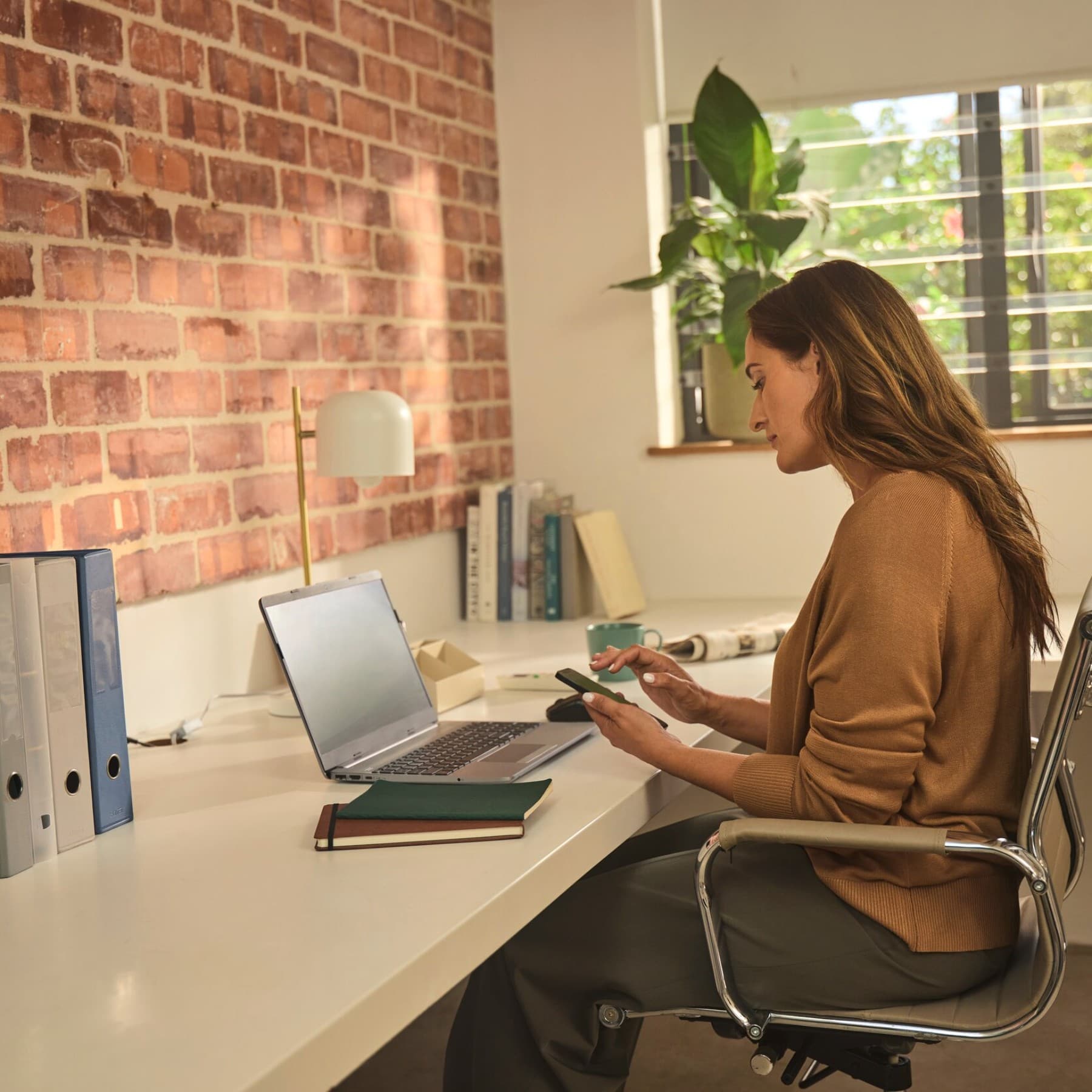 Eine Frau sitzt an einem Schreibtisch und arbeitet an einem Laptop.
