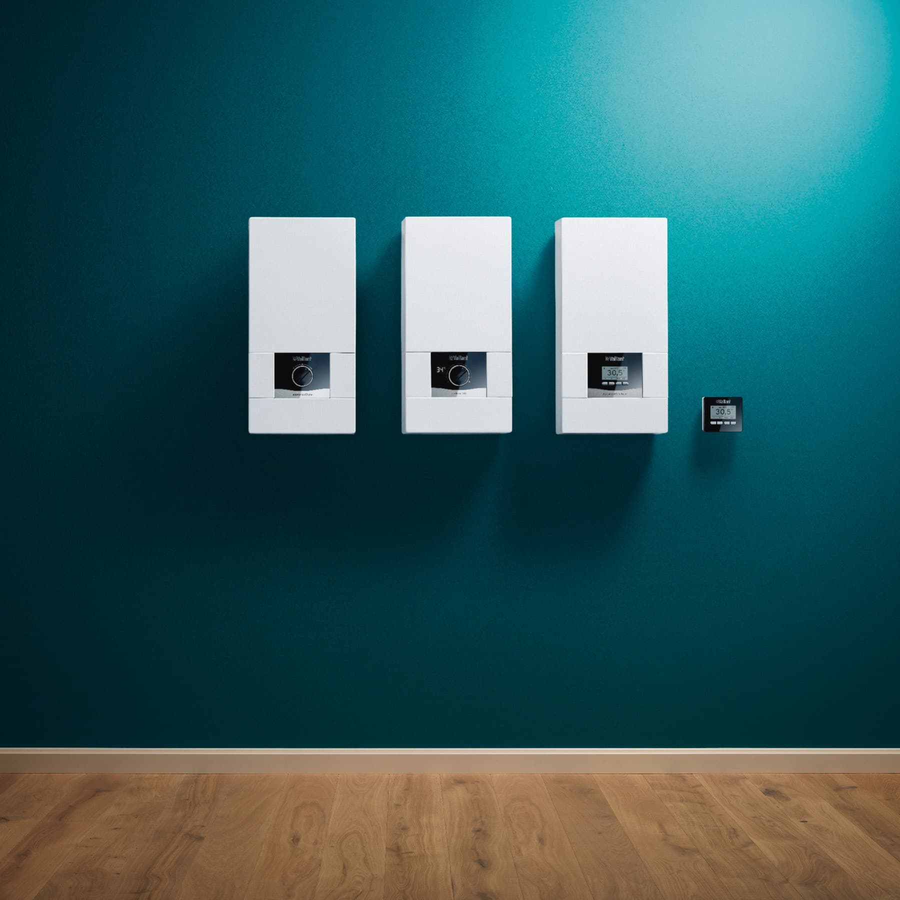 Mehrere Vaillant Durchlauferhitzer hängen nebeneinander an einer grünen Wand.