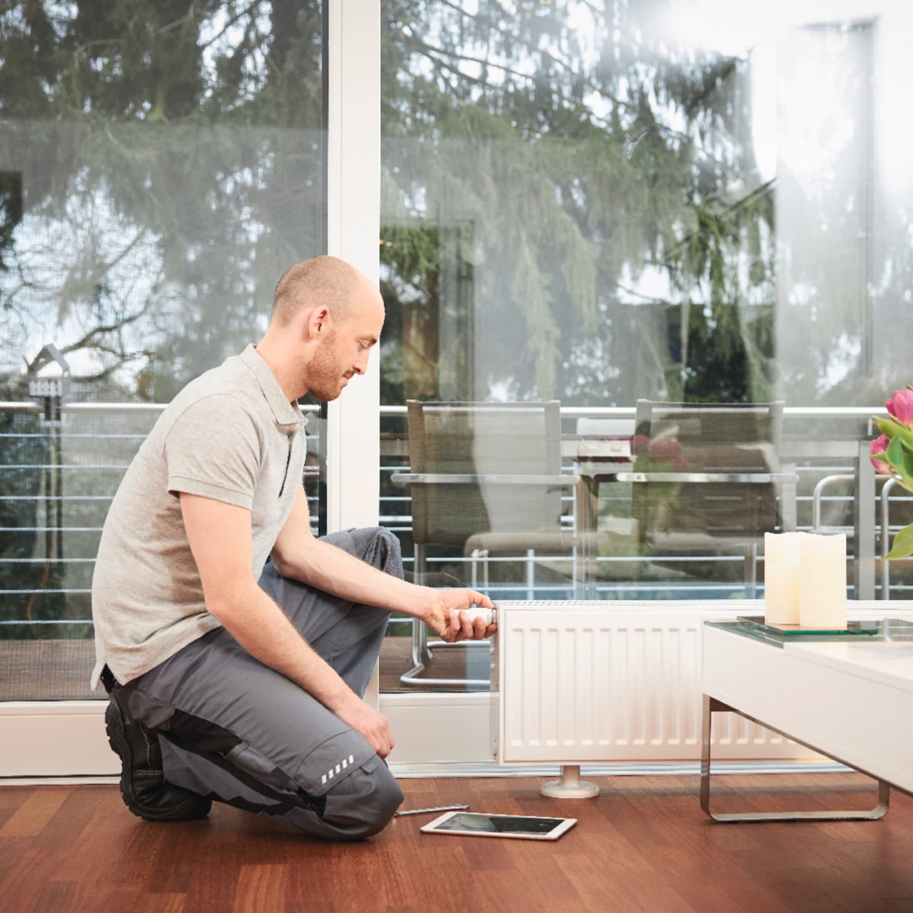 Fachhandwerker bedient Thermostat am Heizkörper.