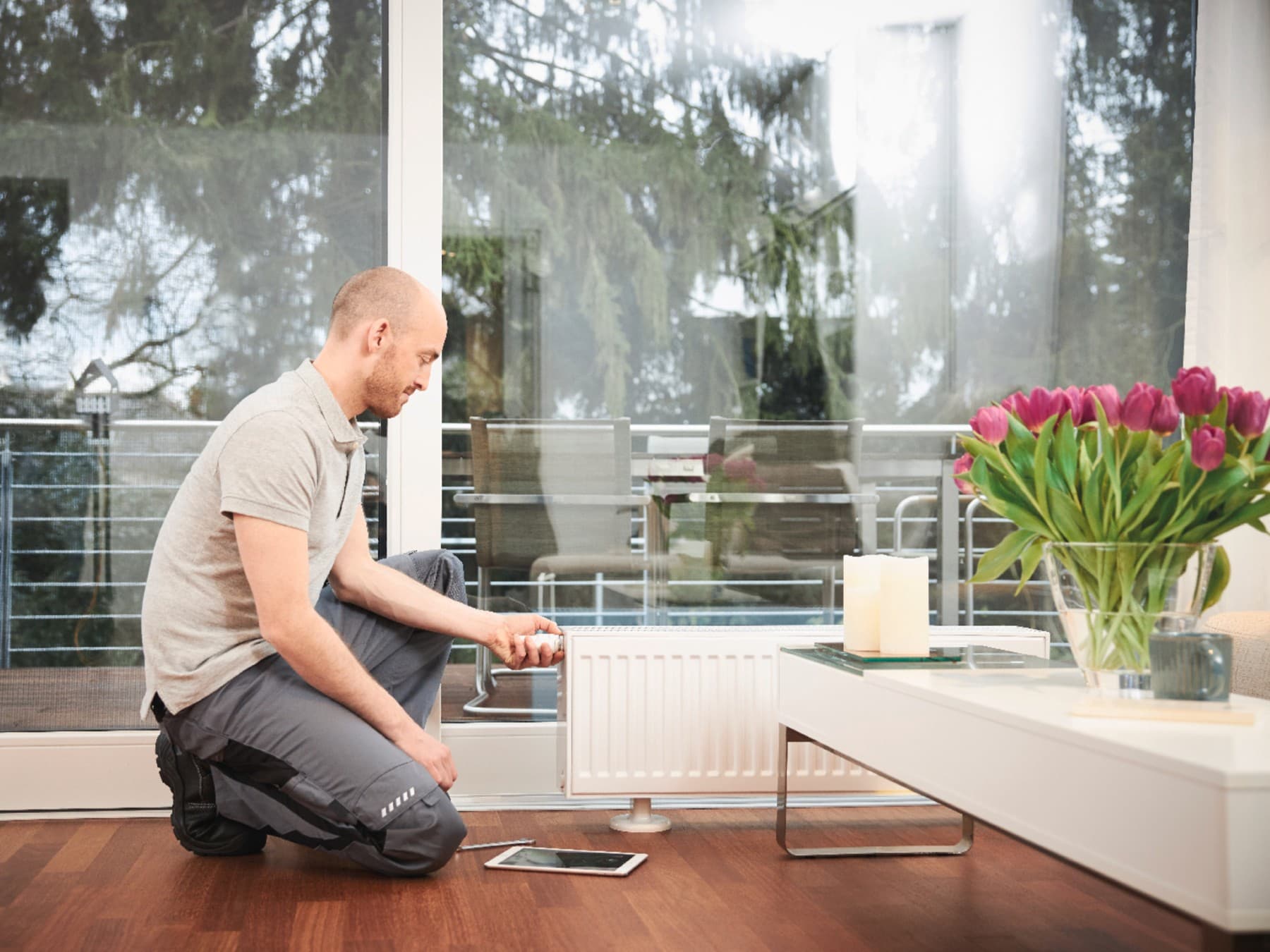 Fachhandwerker bedient Thermostat am Heizkörper.