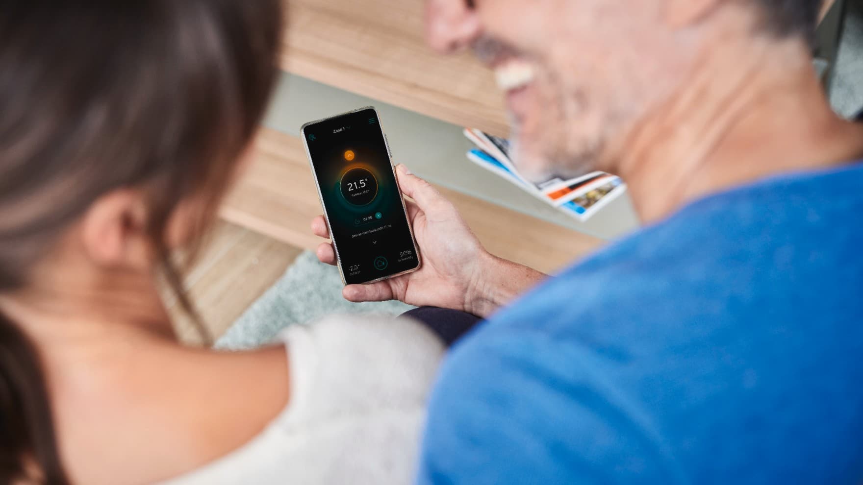 Zwei Menschen schauen auf ein Smartphone, mit dem die Temperatur der Heizung geregelt werden kann.
