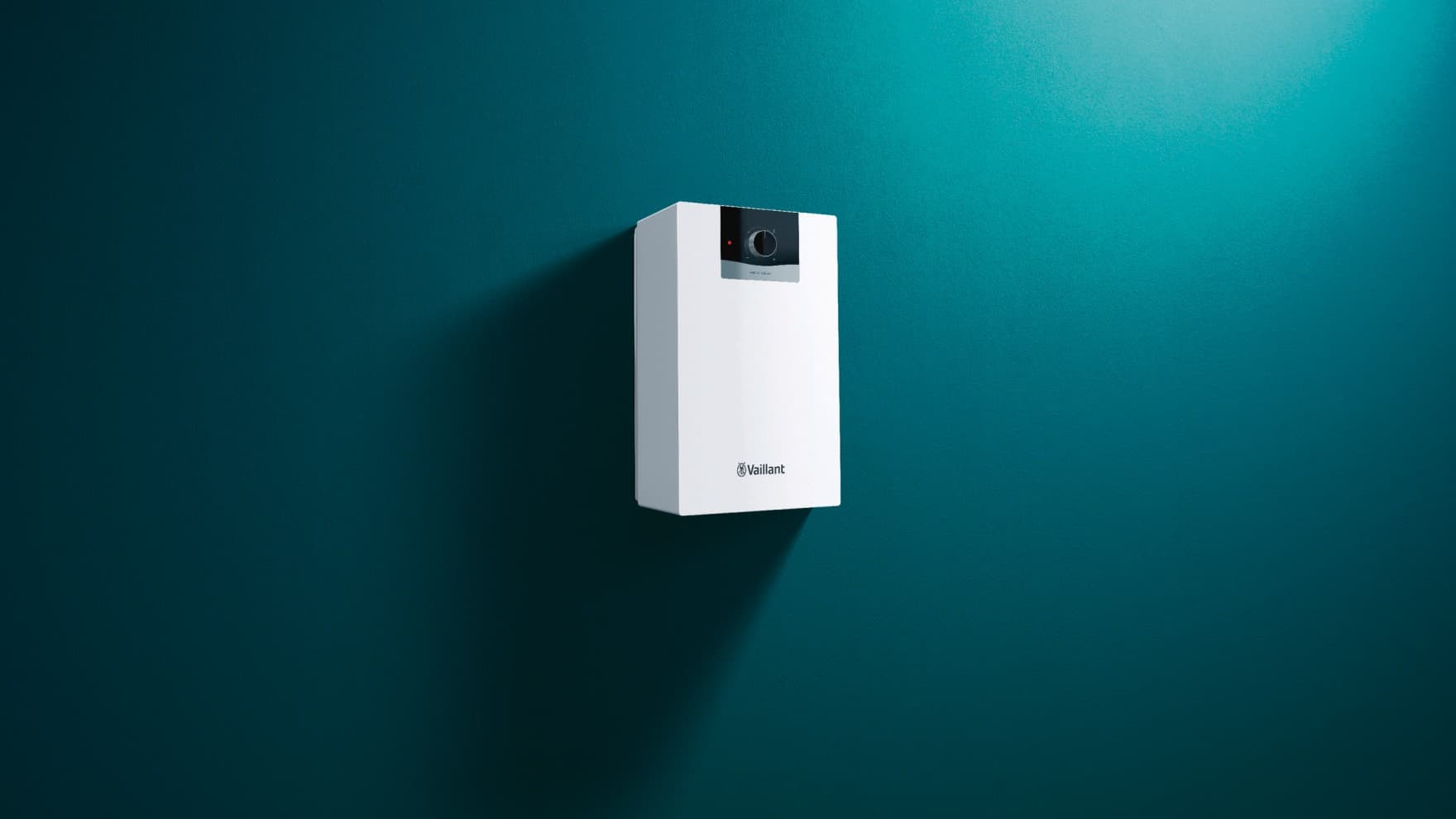 Ein Warmwasserspeicher von Vaillant hängt an einer grünen Wand.