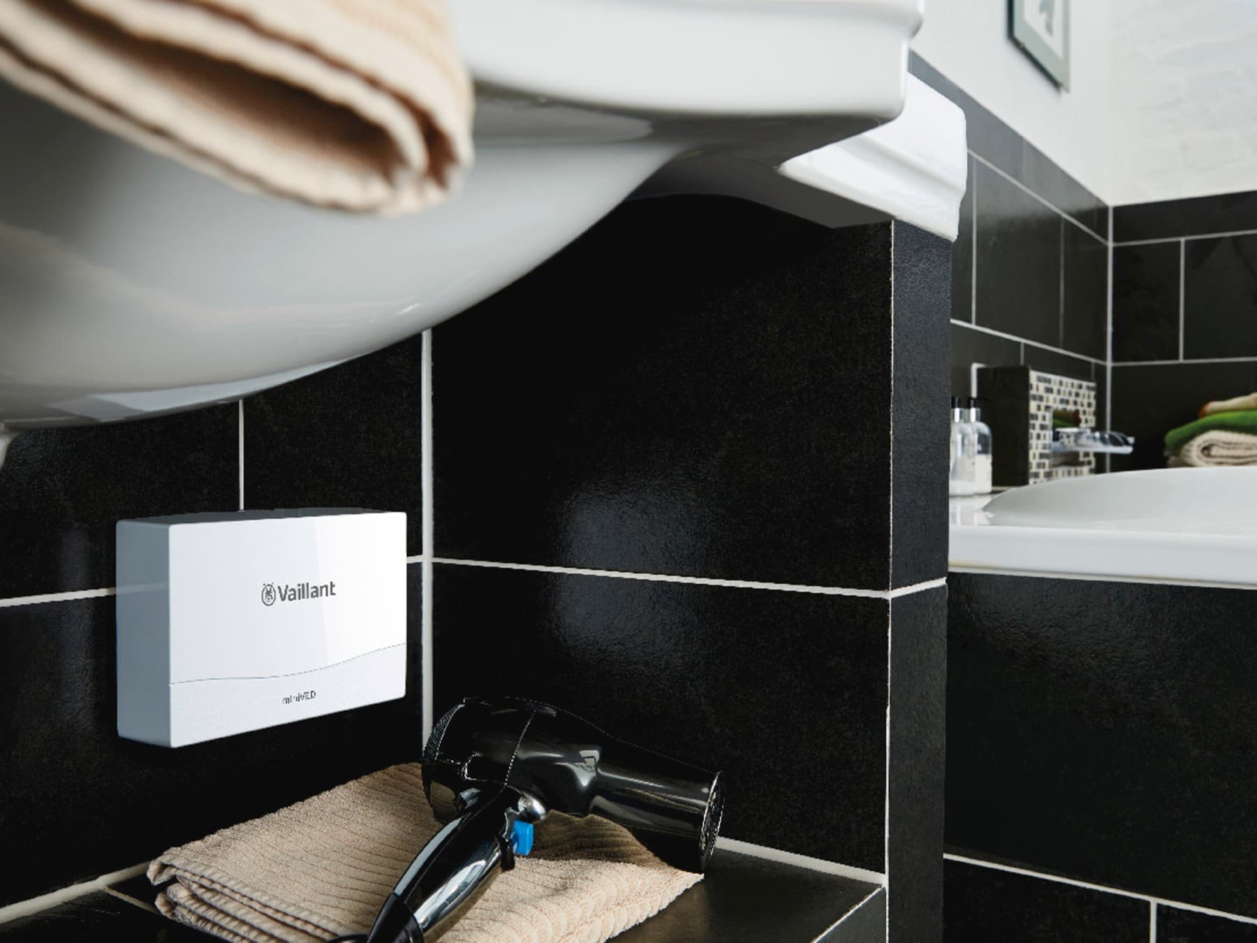 Hydraulischer Durchlauferhitzer miniVED hängend unter einem Einzelwaschbecken in einem Gäste-WC