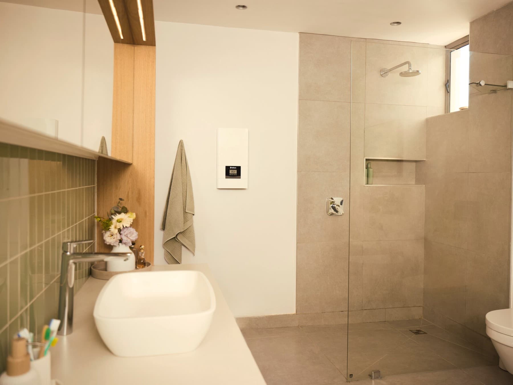 Vaillant Durchlauferhitzer electronicVED hängt in einem Badezimmer links neben der Dusche an einer Wand