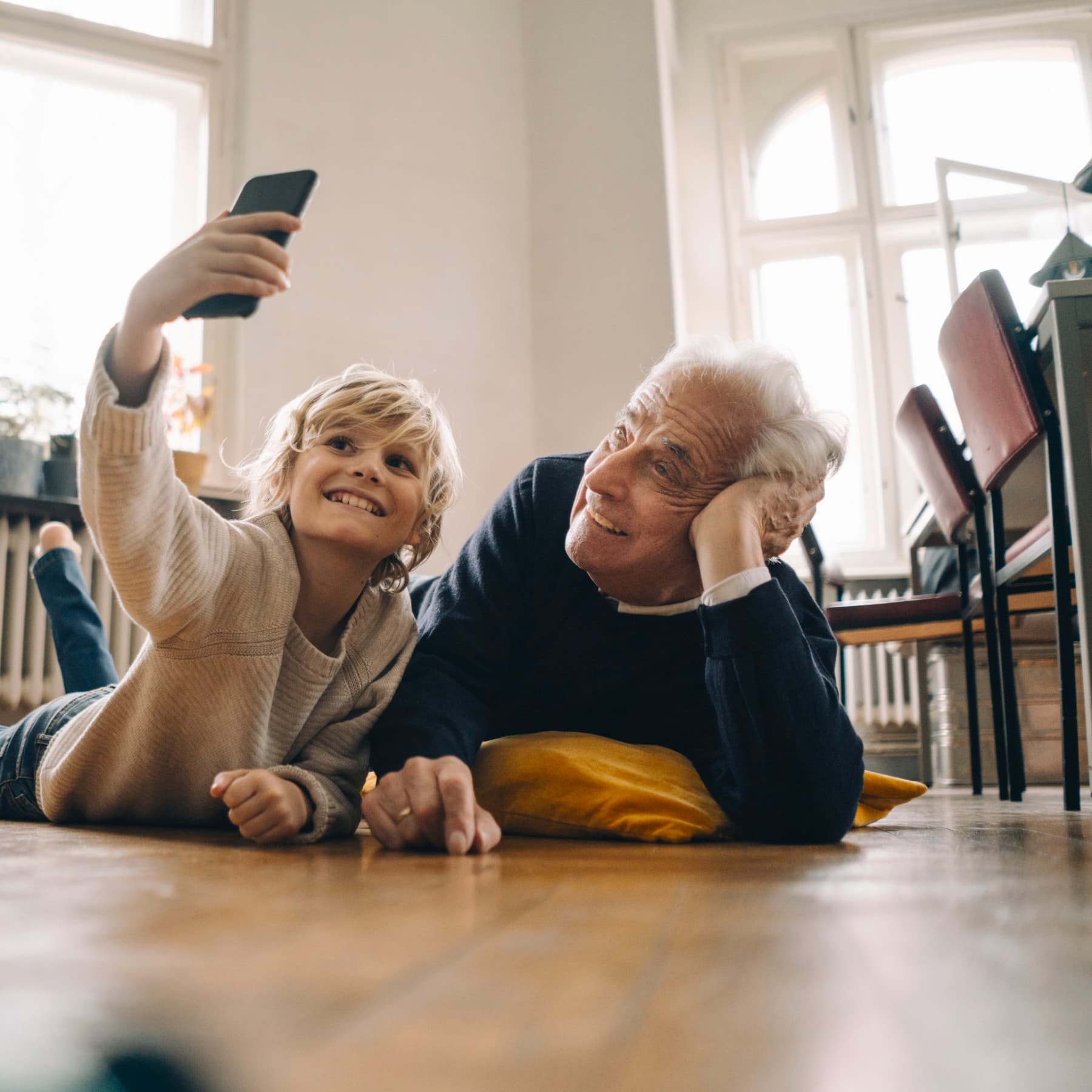 Ein Mann und ein Kind liegen auf einem Holzfußboden im Wohnzimmer.