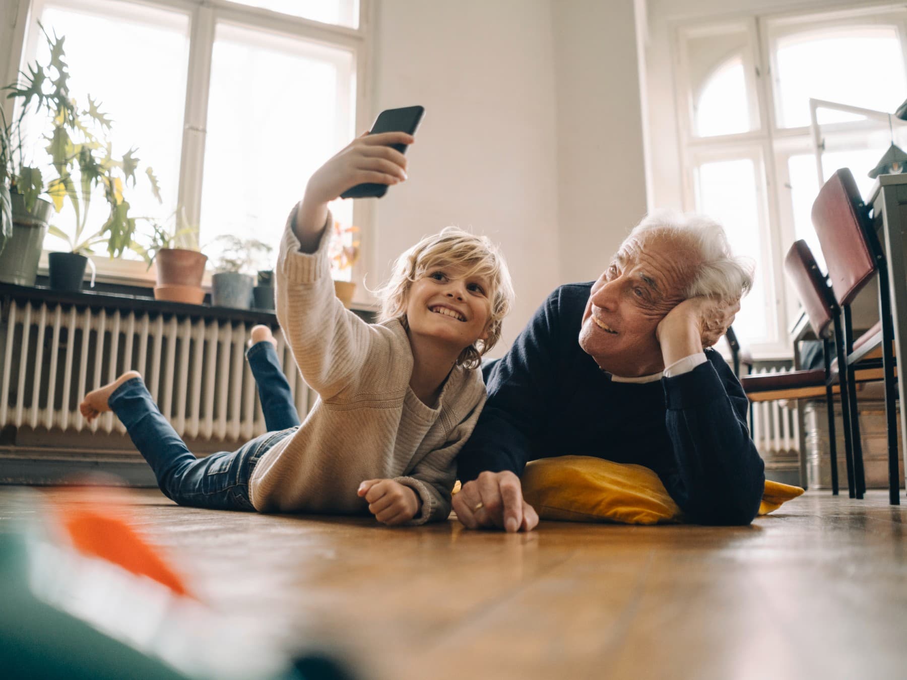 Großvater und Enkelkind liegen auf dem Boden und machen ein Foto