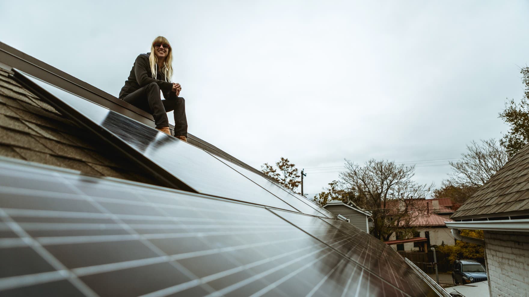Frau sitzt auf Dach mit Photovoltaikanlage