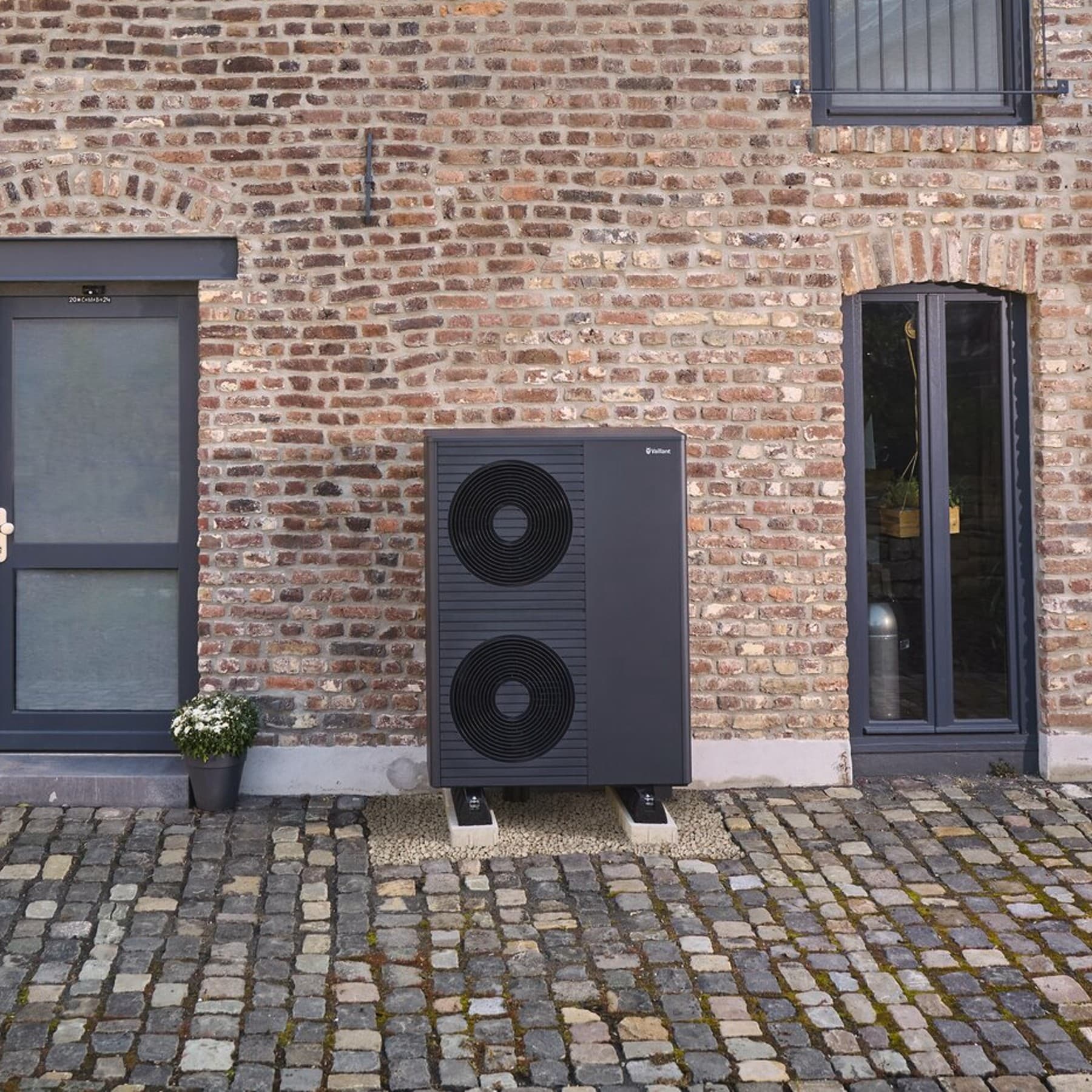 Schwarzgraue Vaillant Wärmepumpe vor einer Hauswand und Photovoltaik auf dem Dach