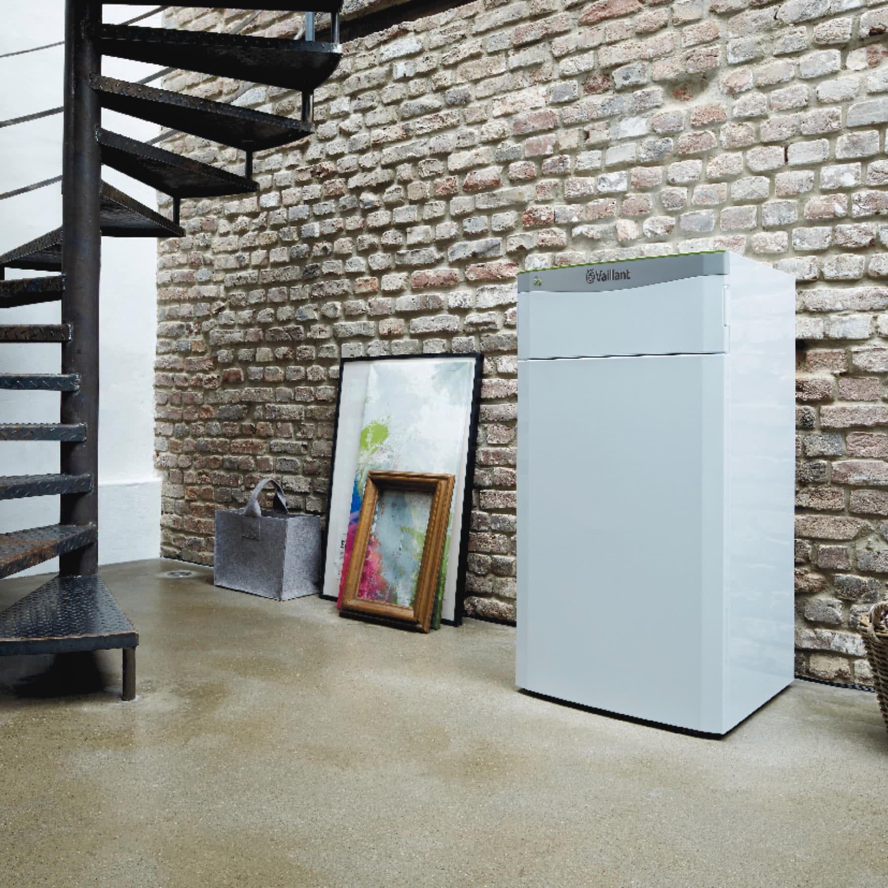 Eine Wasserwärmepumpe im Keller neben einer Wendeltreppe eines Hauses.