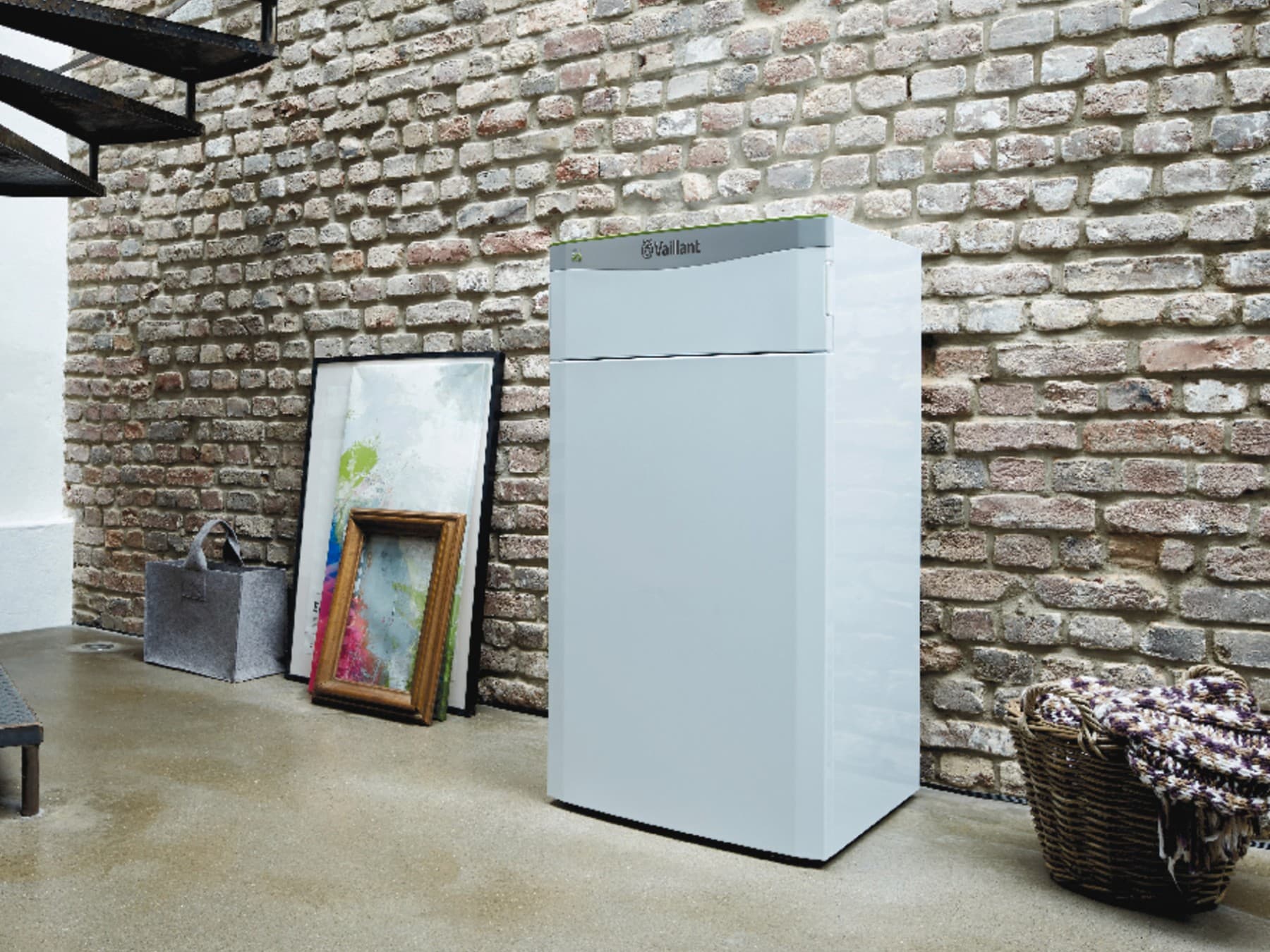 Die Wärmepumpe flexoTHERM exclusive von Vaillant steht rechts neben einer Kellertreppe vor einer Backsteinwand