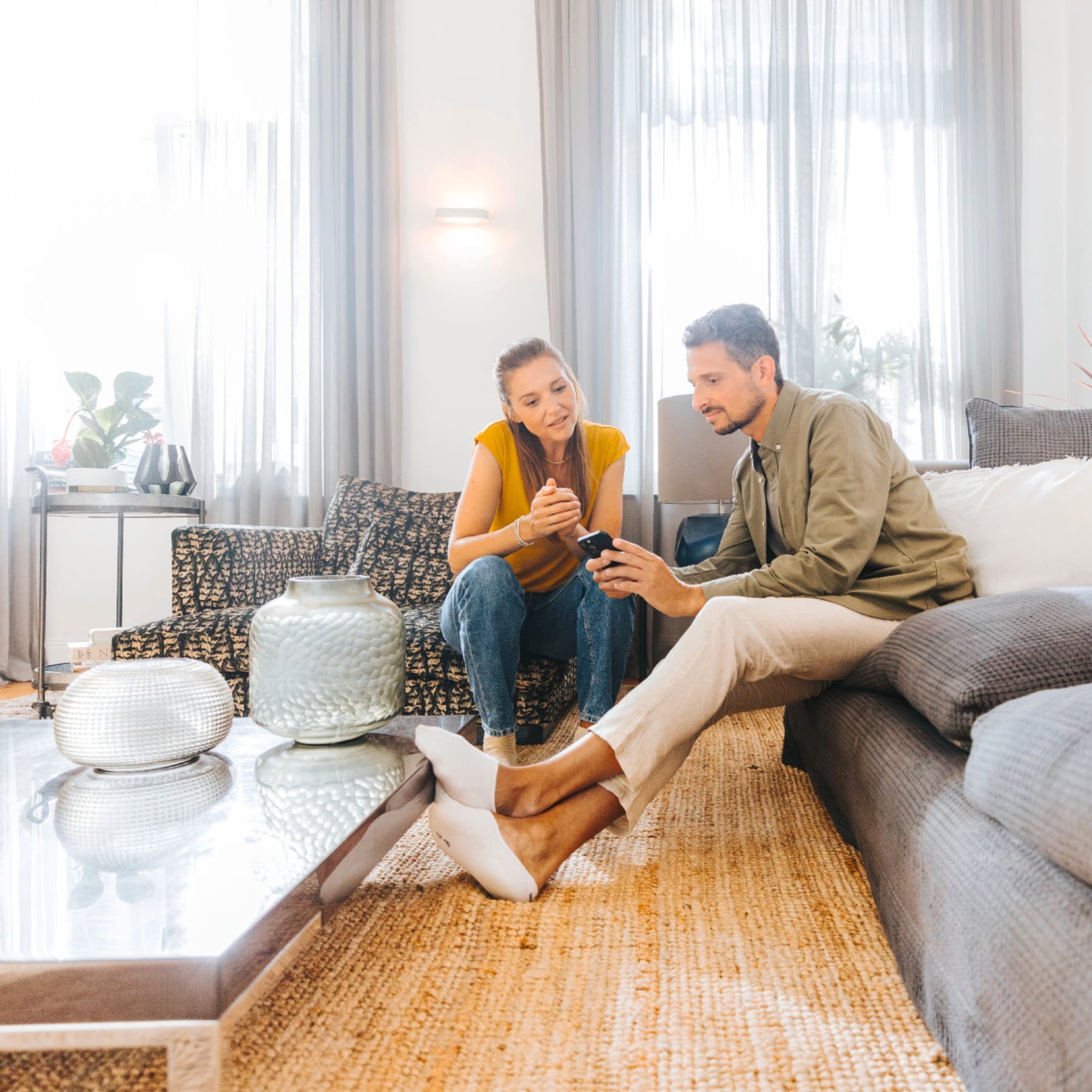 Eine Frau und ein Mann sitzen auf dem Sofa und schauen auf ein Smartphone.