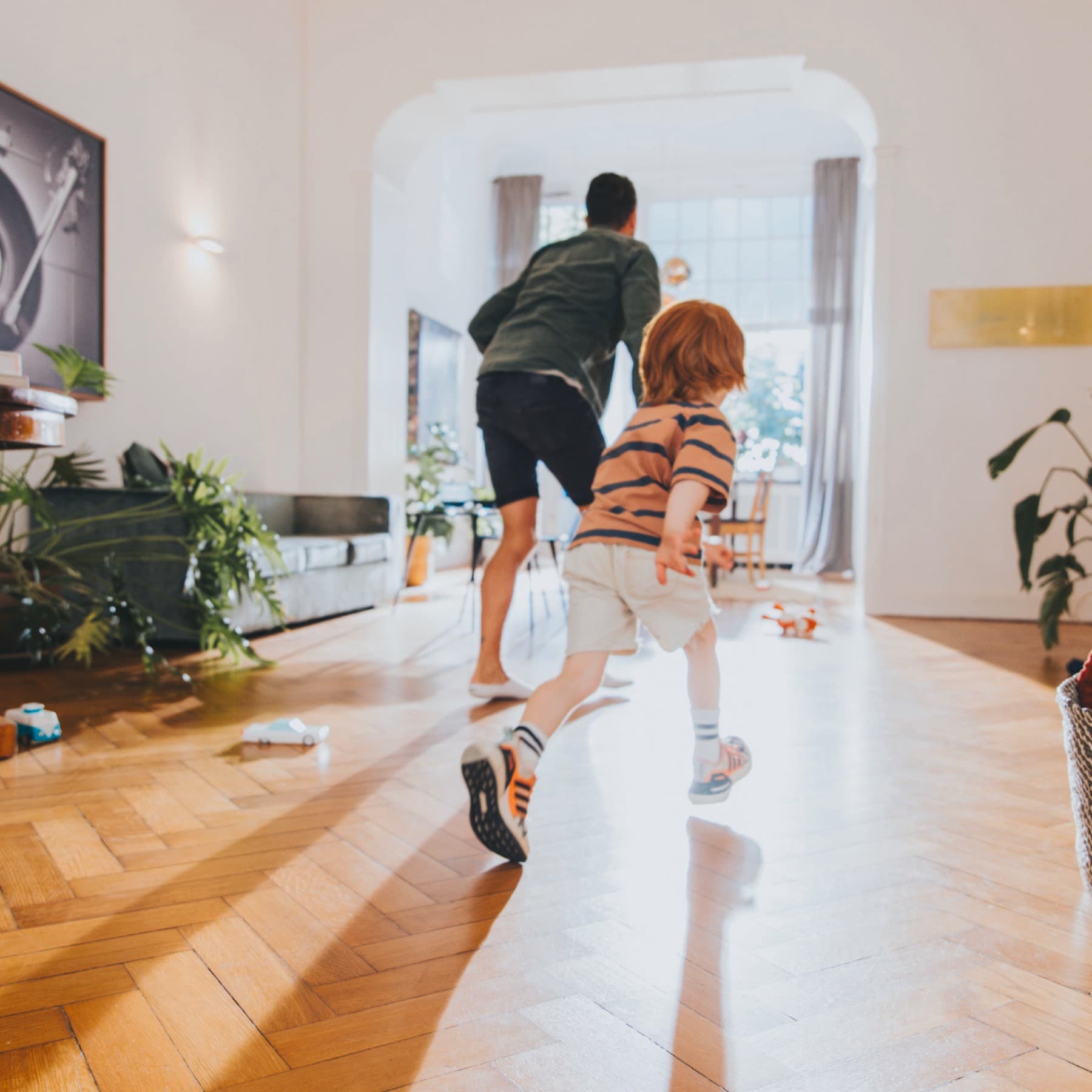 Vater und Sohn spielen zusammen in einem hell beleuchteten Wohnzimmer.