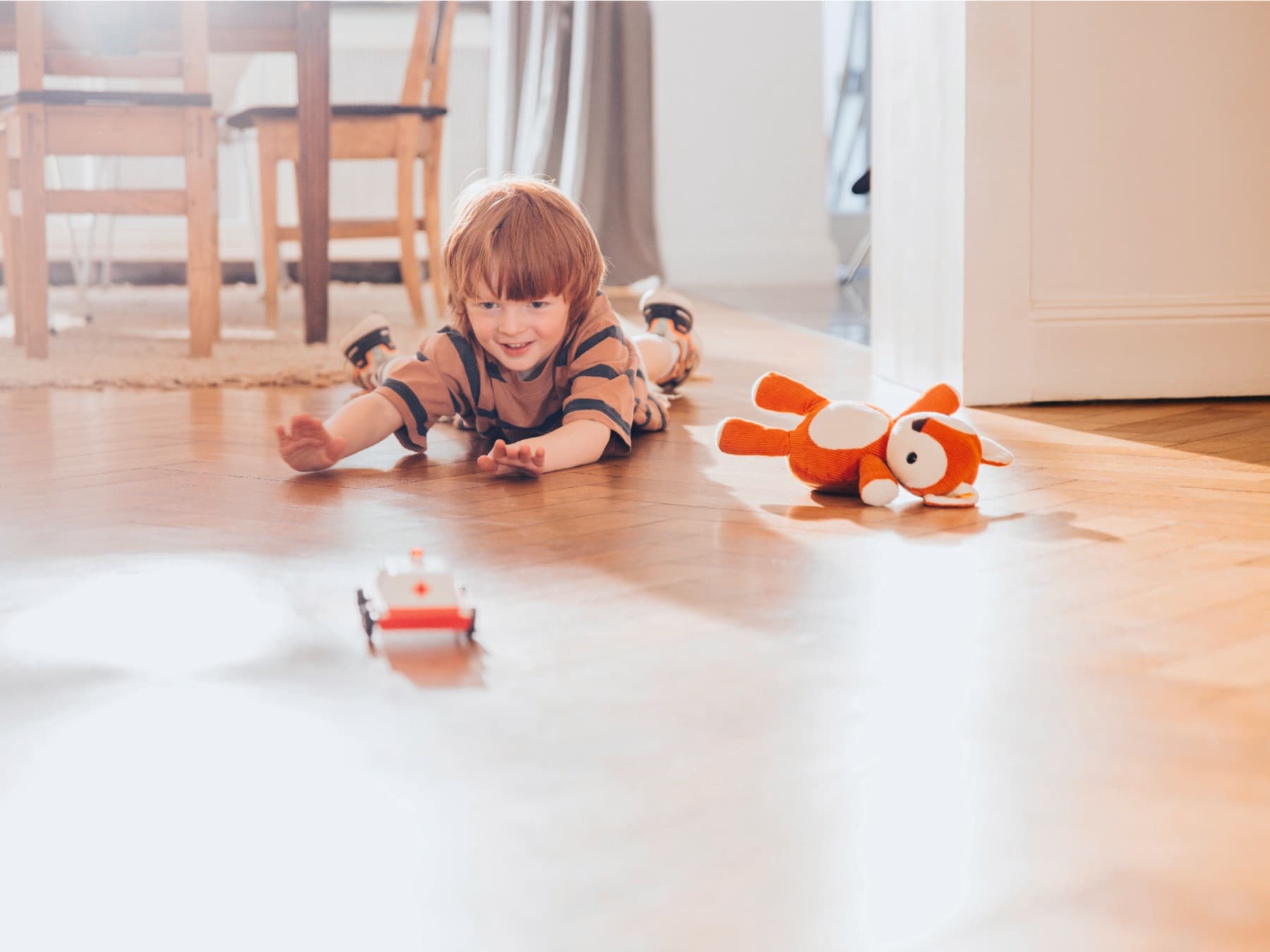 Ein Junge spielt mit Kinerspielzeug auf einem Holzfußboden.