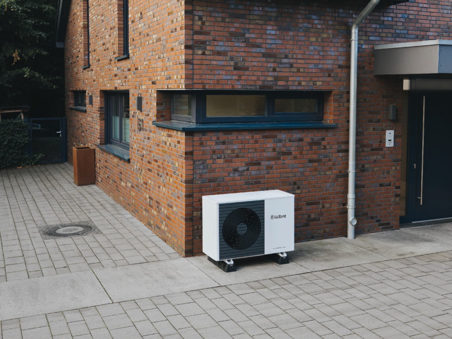 Sanierter Altbau, vor dem eine Vaillant Wärmepumpen Außeneinheit steht