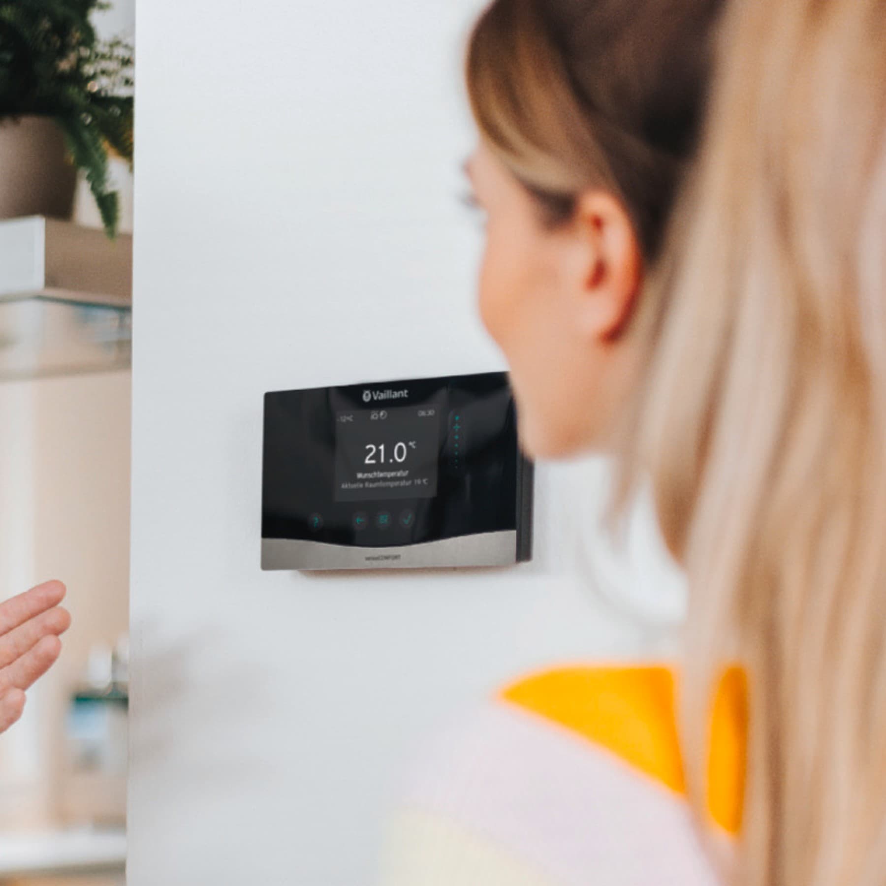 Ein Vaillant Fachhandwerker zeigt einer Frau die Steuerung