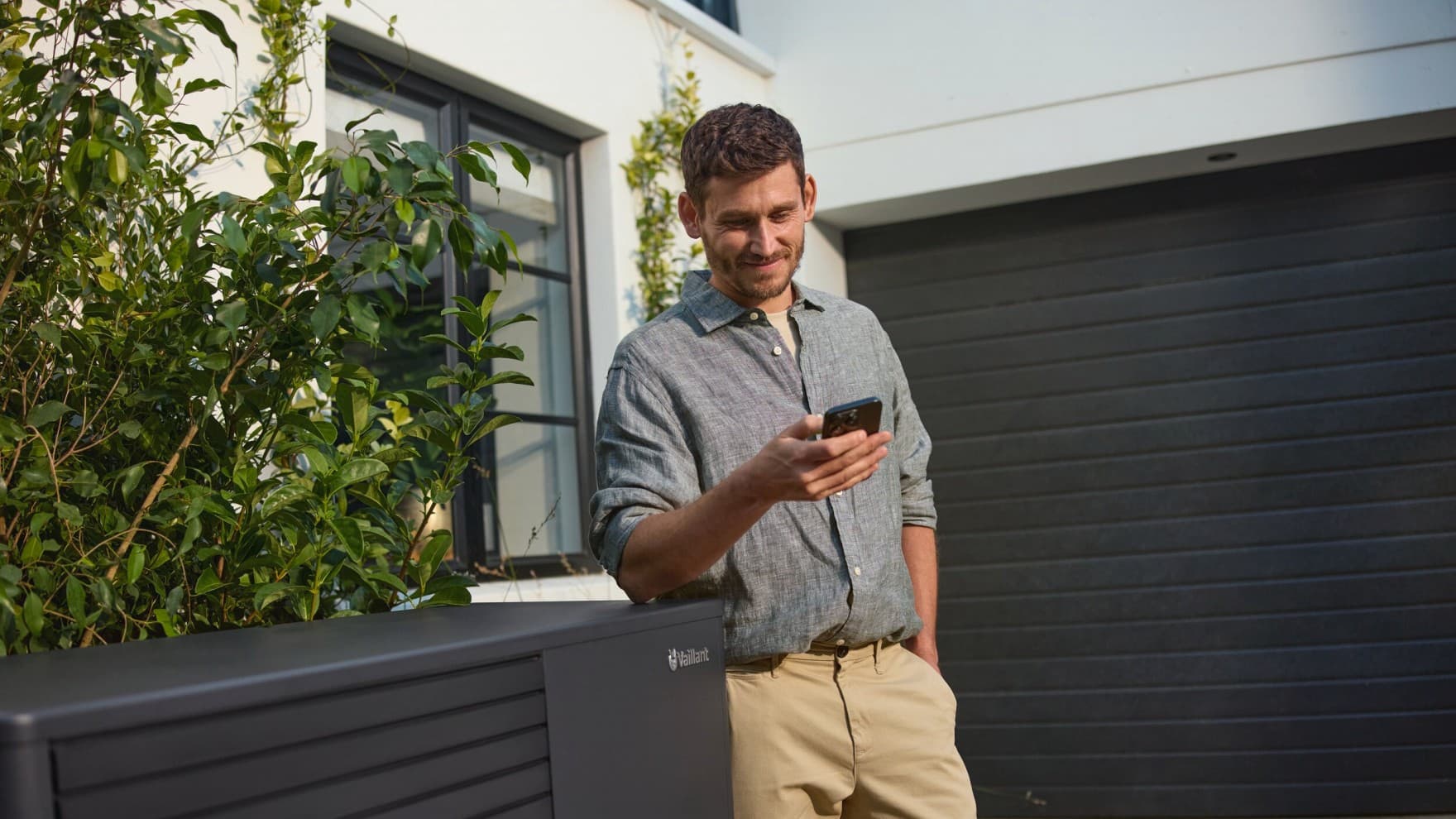 Ein Mann vor seinem Haus mit einem Handy in der Hand