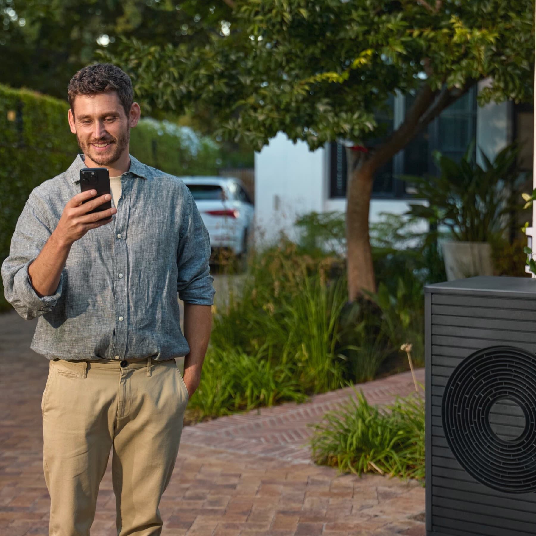 Ein Mann mit Smartphone vor einer Wärmepumpe