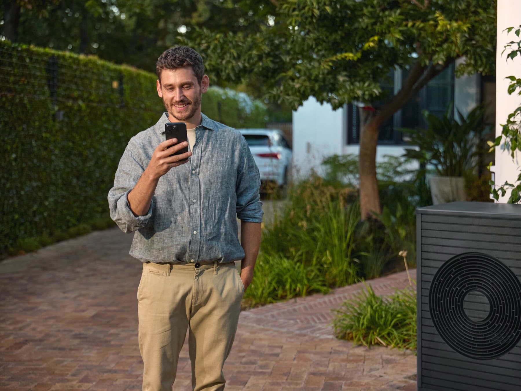 Mann schaut vor einer Vaillant Wärmepumpe auf sein Handy