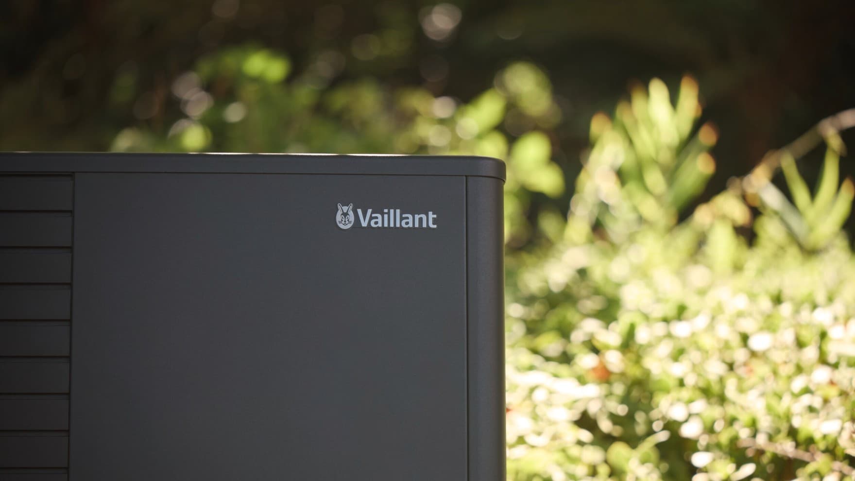 Nahaufnahme aroTHERM plus Wärmepumpe im Garten unter Bäumen