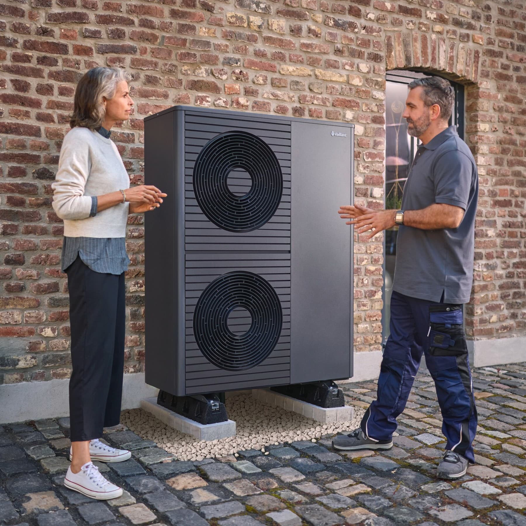 Eine Vaillant aroTHERM plus Wärmepumpe steht auf einem Kiesbett vor einem Einfamilienhaus