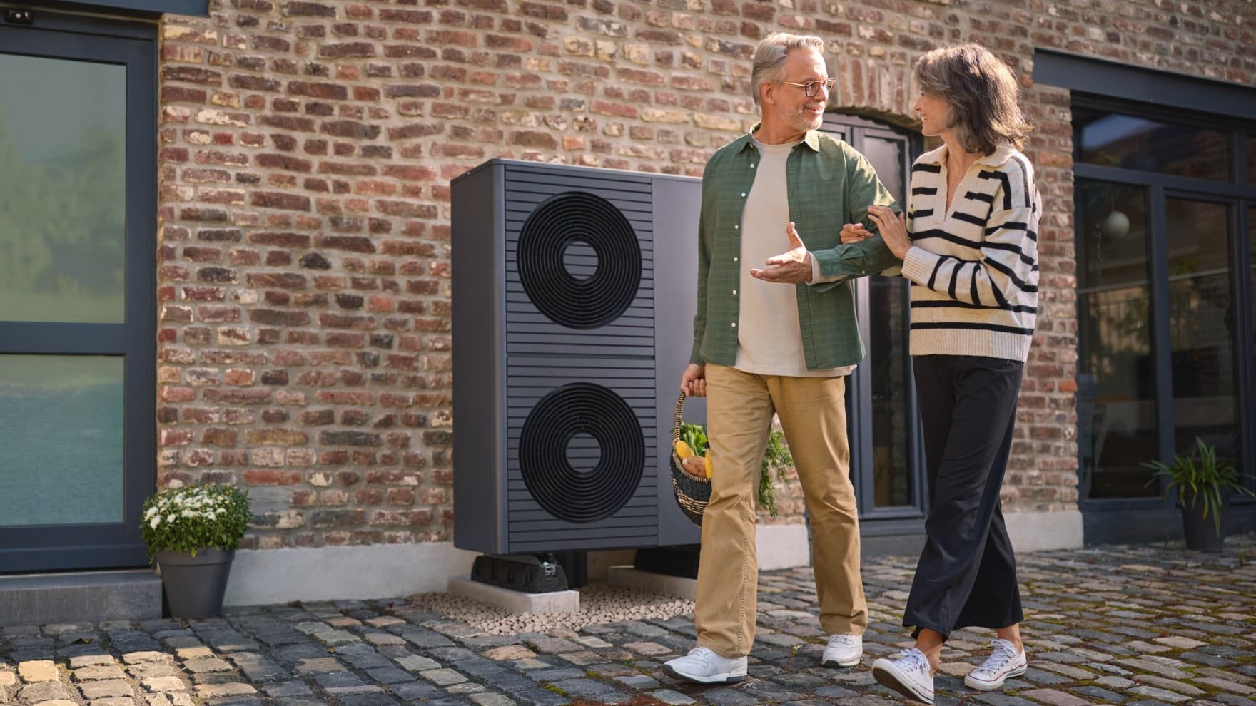 Mann und Frau gehen gemeinsam neben einer Wärmepumpe her.