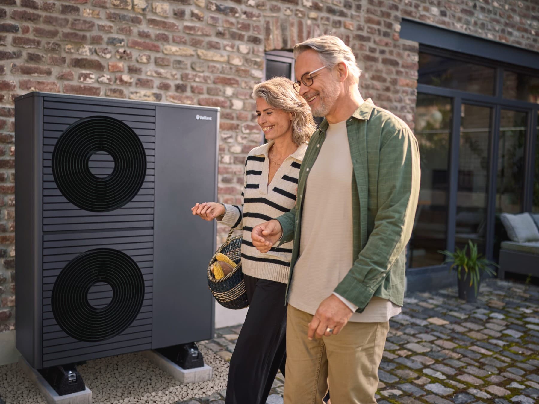Vaillant aroTHERM plus Außeneinheit, im Vordergrund eine Frau mit ihrem Mann im Garten