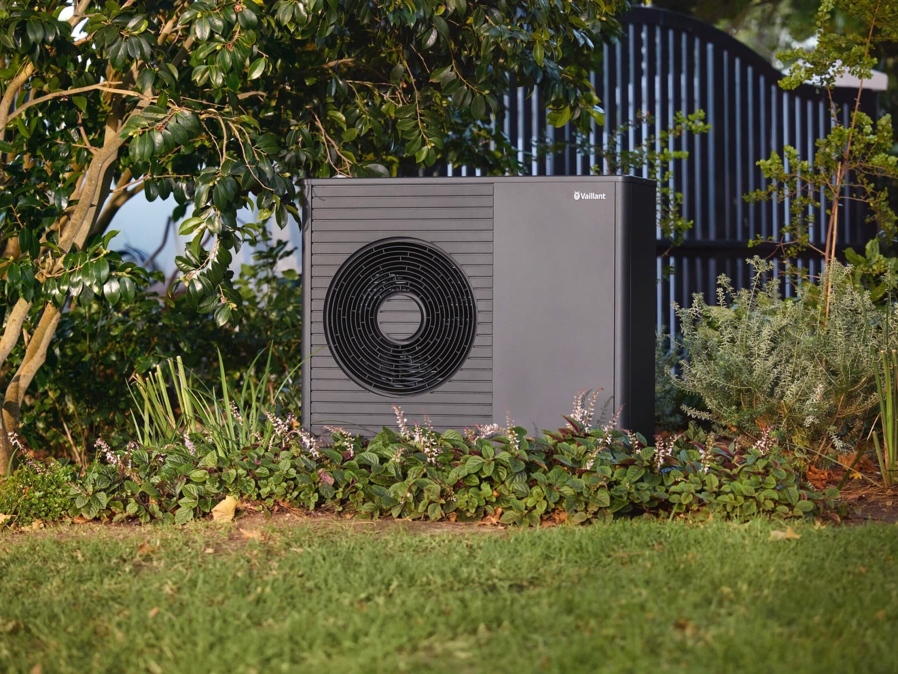Die Vaillant aroTHERM plus Wärmepumpe steht in einem Garten, im grünen Gras.