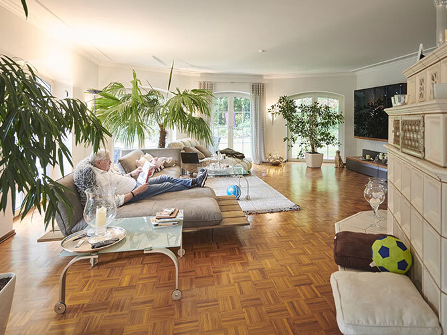 Innenansicht des Wohnzimmers mit lesender Person auf der Couch