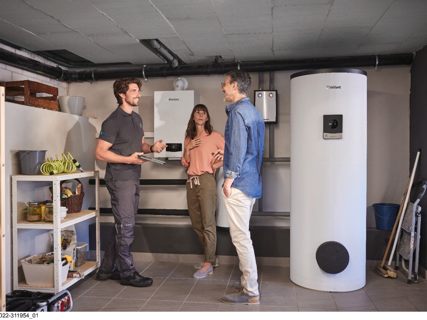 Ehepaar steht mit Vaillant Werkskundendienst-Techniker im Keller vor der neuen Hybridheizung
