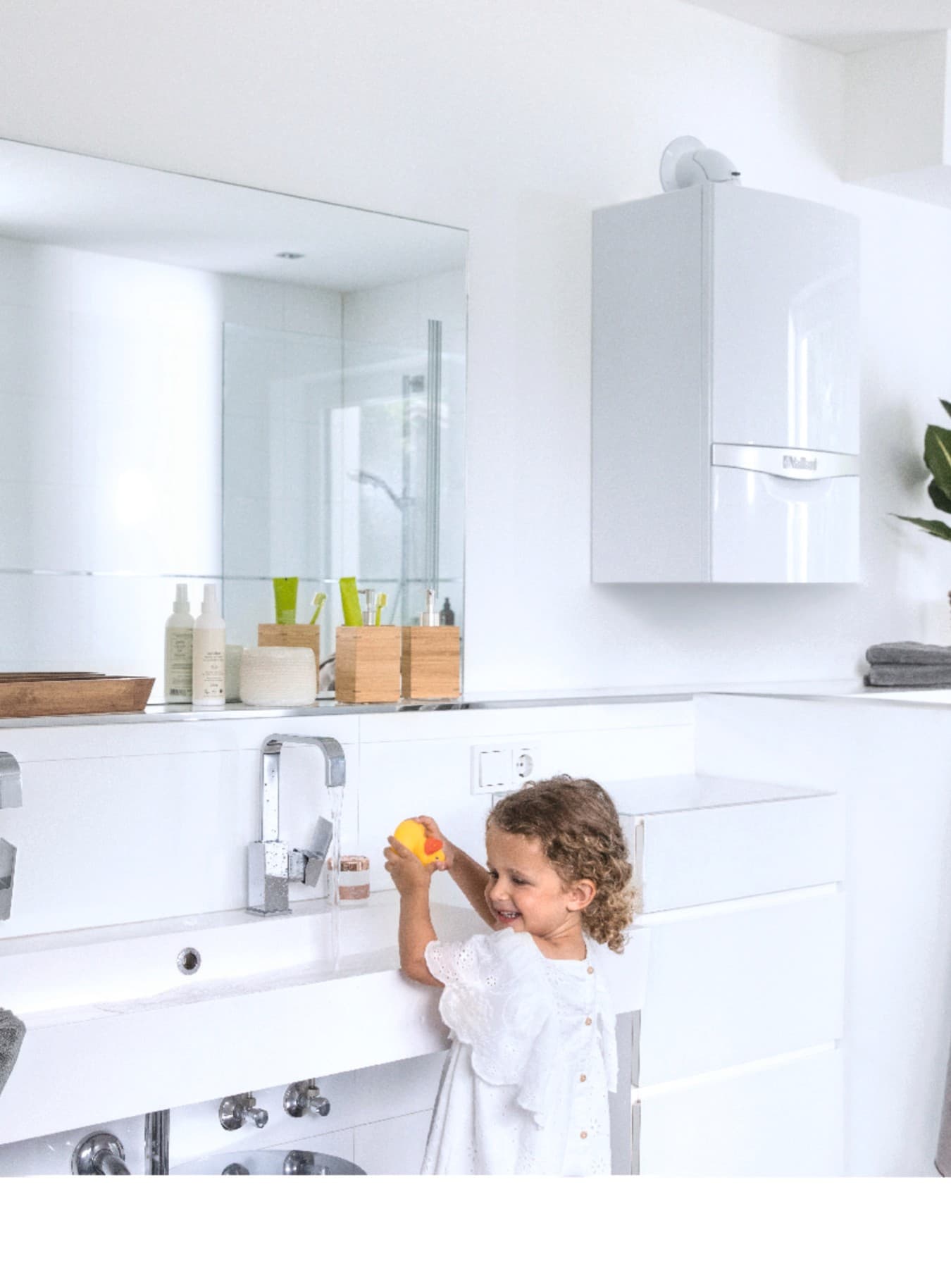 Kind am Waschbecken. Im Hintergrund hängt ein Vaillant Gerät an der Wand.