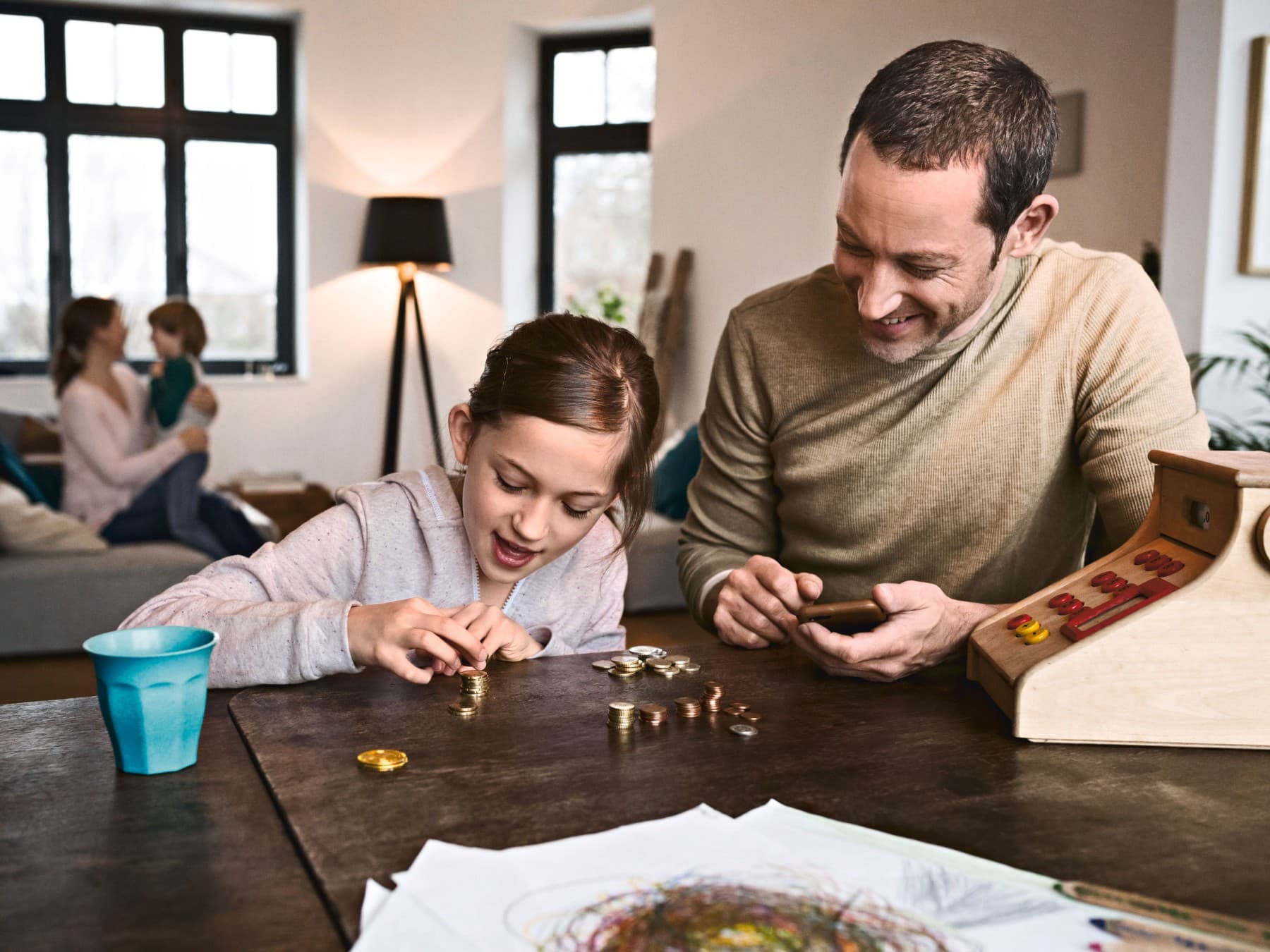 Kind sitzt mit seinem Vater am Tisch und zählt Kleingeld