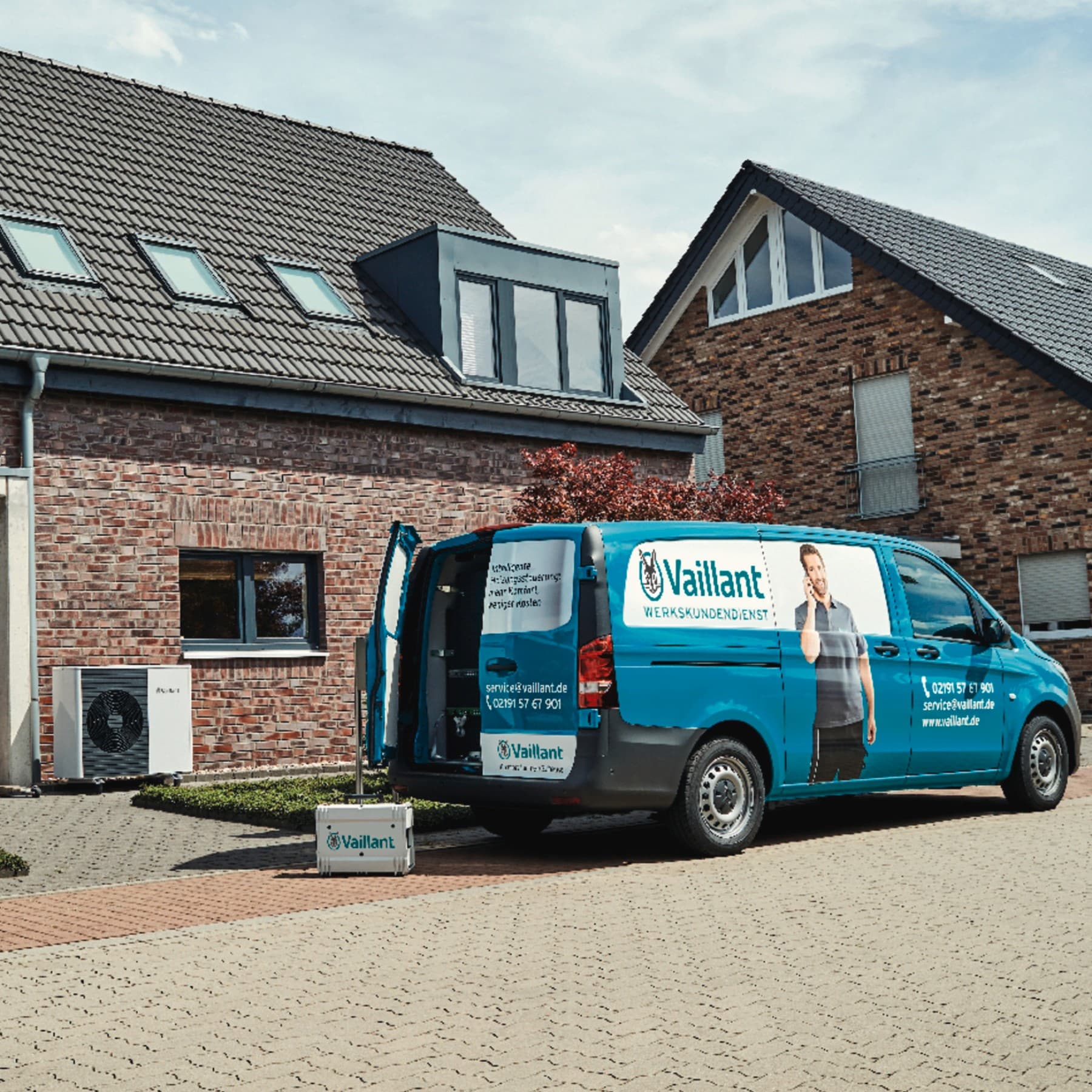 Ein Vaillant Kundendienstauto steht vor einem Einfamilienhaus mit Backsteinfassade.