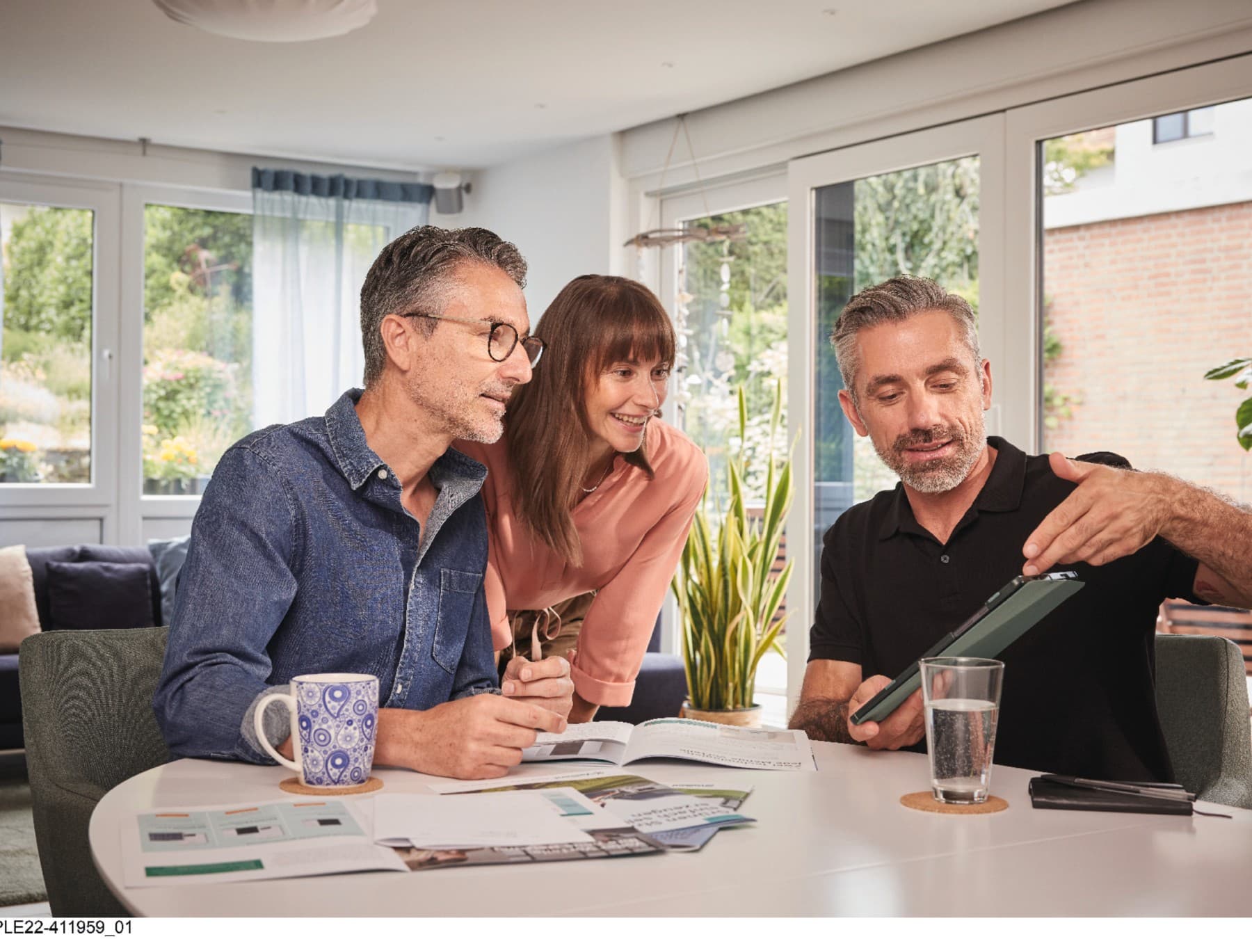 Eine Frau und ein Mann sitzen mit einem Vaillant Fachhandwerker am Küchentisch und lassen sich beraten.