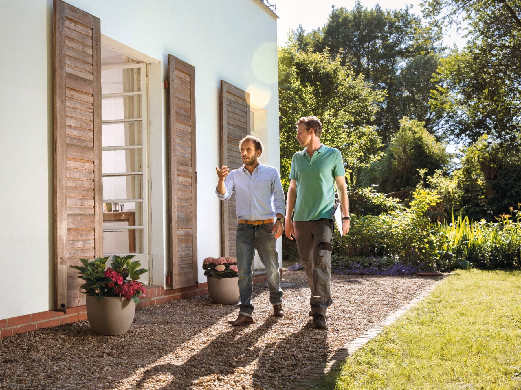 Ein Hauseigentümer mit einem Fachpartner im Beratungsgespräch vor seinem Haus.