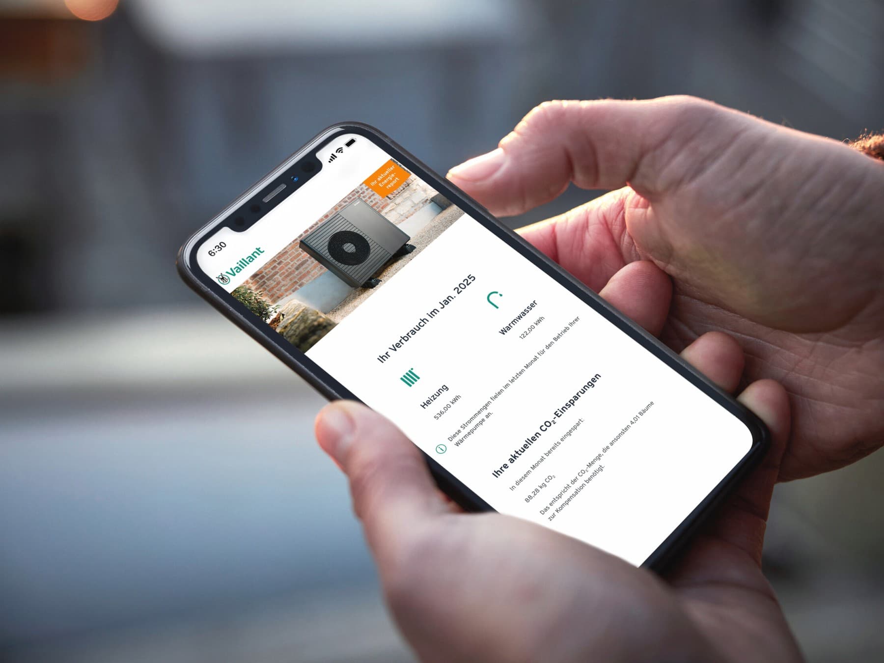 Zwei Hände halten ein Smartphone. Auf dem Display ist die Oberfläche von OptimierungPLUS zu erkennen, in dem man lesen kann, wie hoch der Verbrauch im Januar 2025 war.